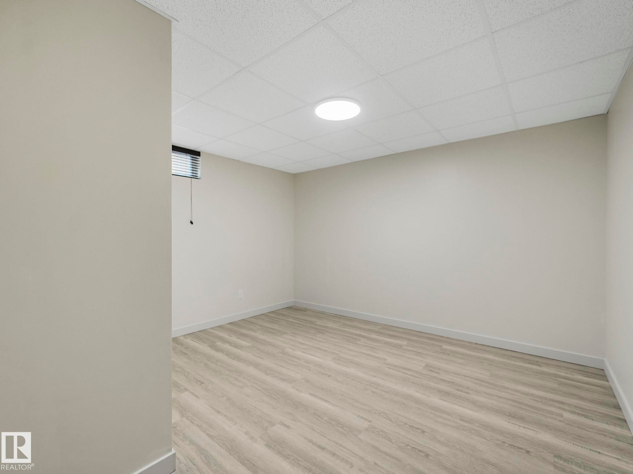 Spacious room featuring light-toned walls, a drop ceiling, recessed lighting, and a small window with blinds - 7607 70 Avenue, Edmonton, AB - Indoor Photo Showing Other Room