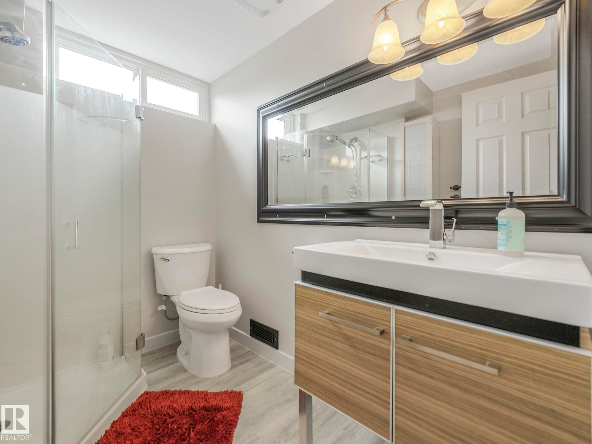 Contemporary bathroom featuring a floating vanity with a vessel sink, single-handle faucet, and wood-finish cabinetry - 7607 70 Avenue, Edmonton, AB - Indoor Photo Showing Bathroom