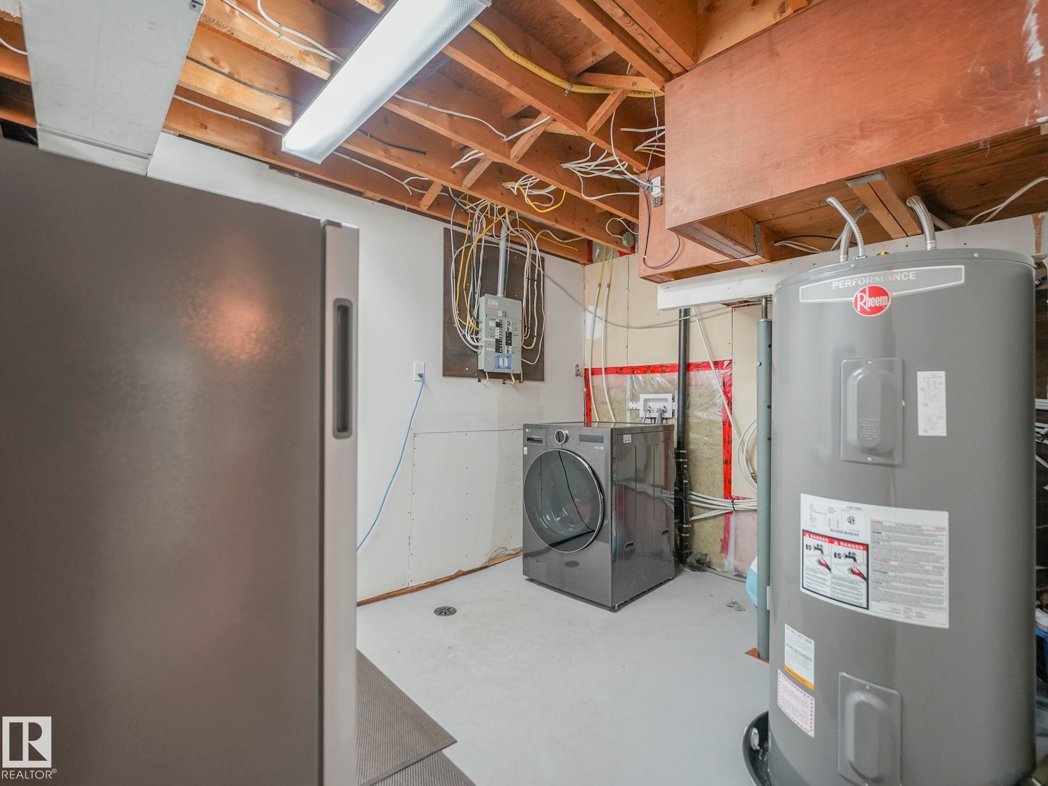 Laundry area featuring exposed ceiling joists, a water heater, and a front-loading washer/dryer combo. - 7607 70 Avenue, Edmonton, AB - Indoor