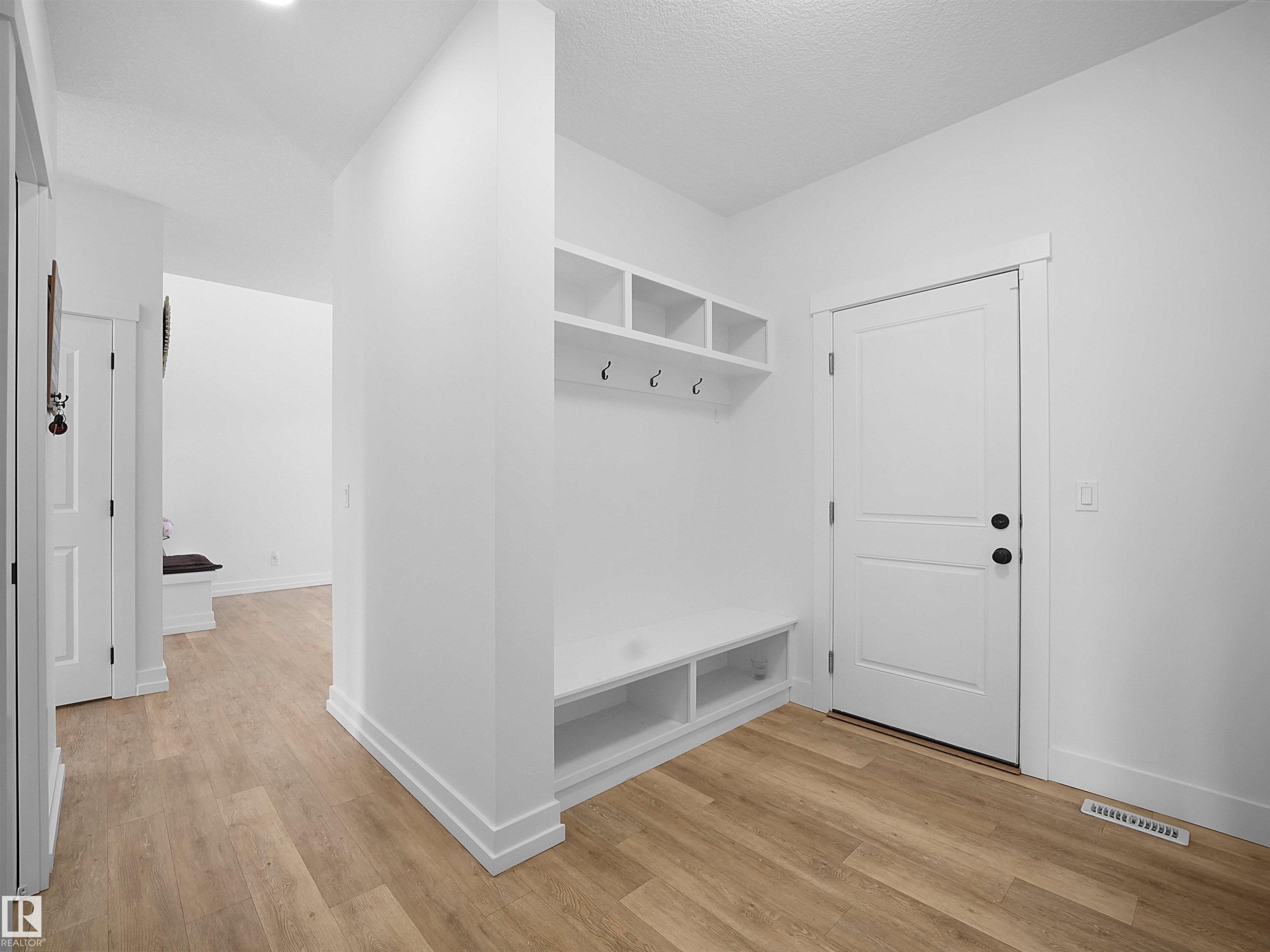 Entryway featuring light wood-style flooring, white walls, and built-in storage with shelves, hooks, and a bench - 4231 Charles Close, Edmonton, AB - Indoor Photo Showing Other Room
