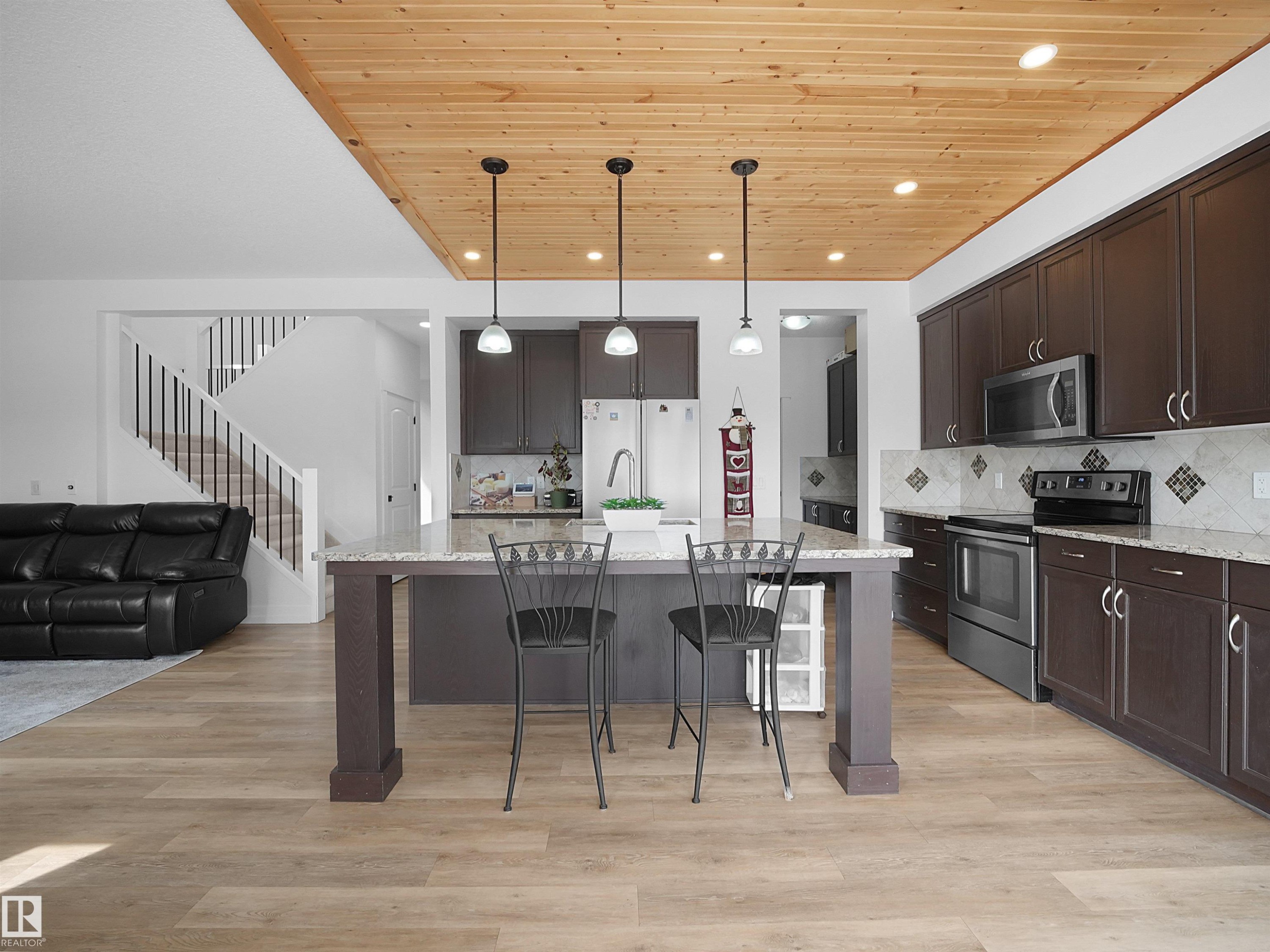 The kitchen features dark wood cabinetry, stainless steel appliances, and a tiled backsplash - 4231 Charles Close, Edmonton, AB - Indoor Photo Showing Kitchen With Upgraded Kitchen