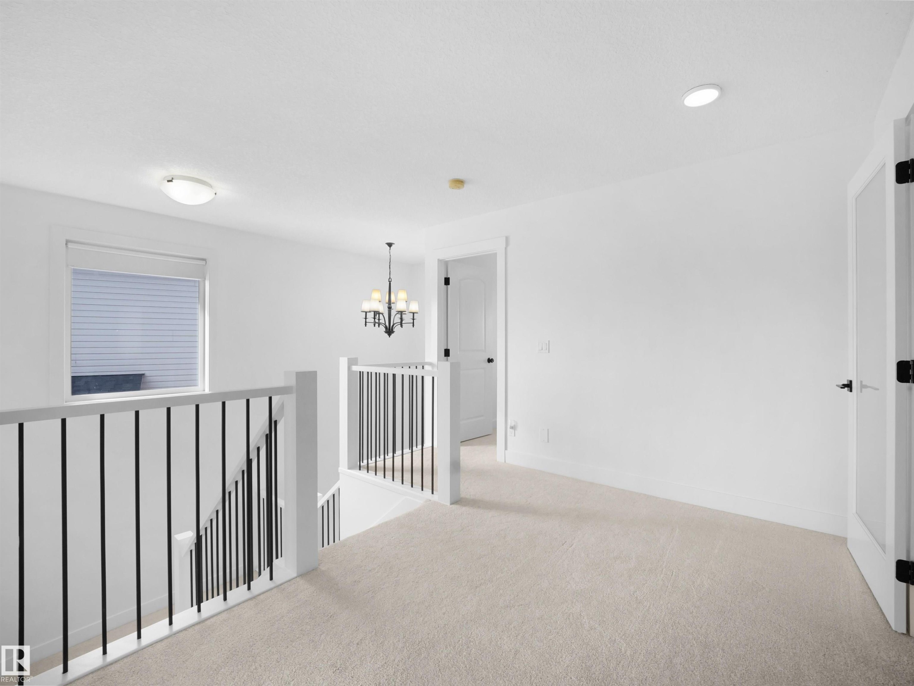 This property features a bright hallway with light-colored carpeting, a window with blinds, and white walls - 4231 Charles Close, Edmonton, AB - Indoor Photo Showing Other Room