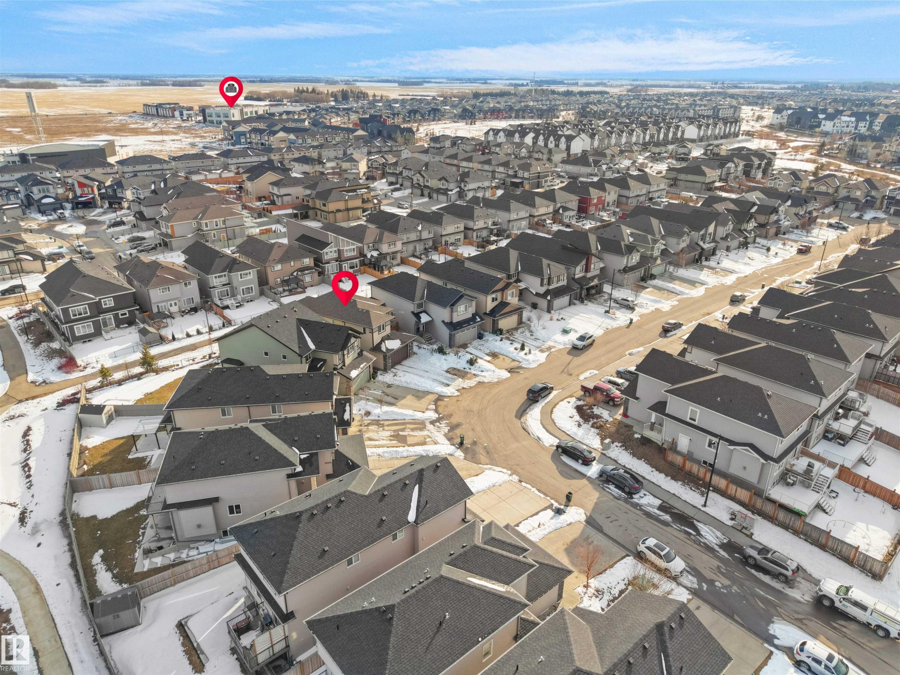 Aerial view of the neighborhood showcasing residential properties with grey roofs and varied exterior finishes, alongside a paved street and surrounding open land - 4231 Charles Close, Edmonton, AB - Outdoor With View