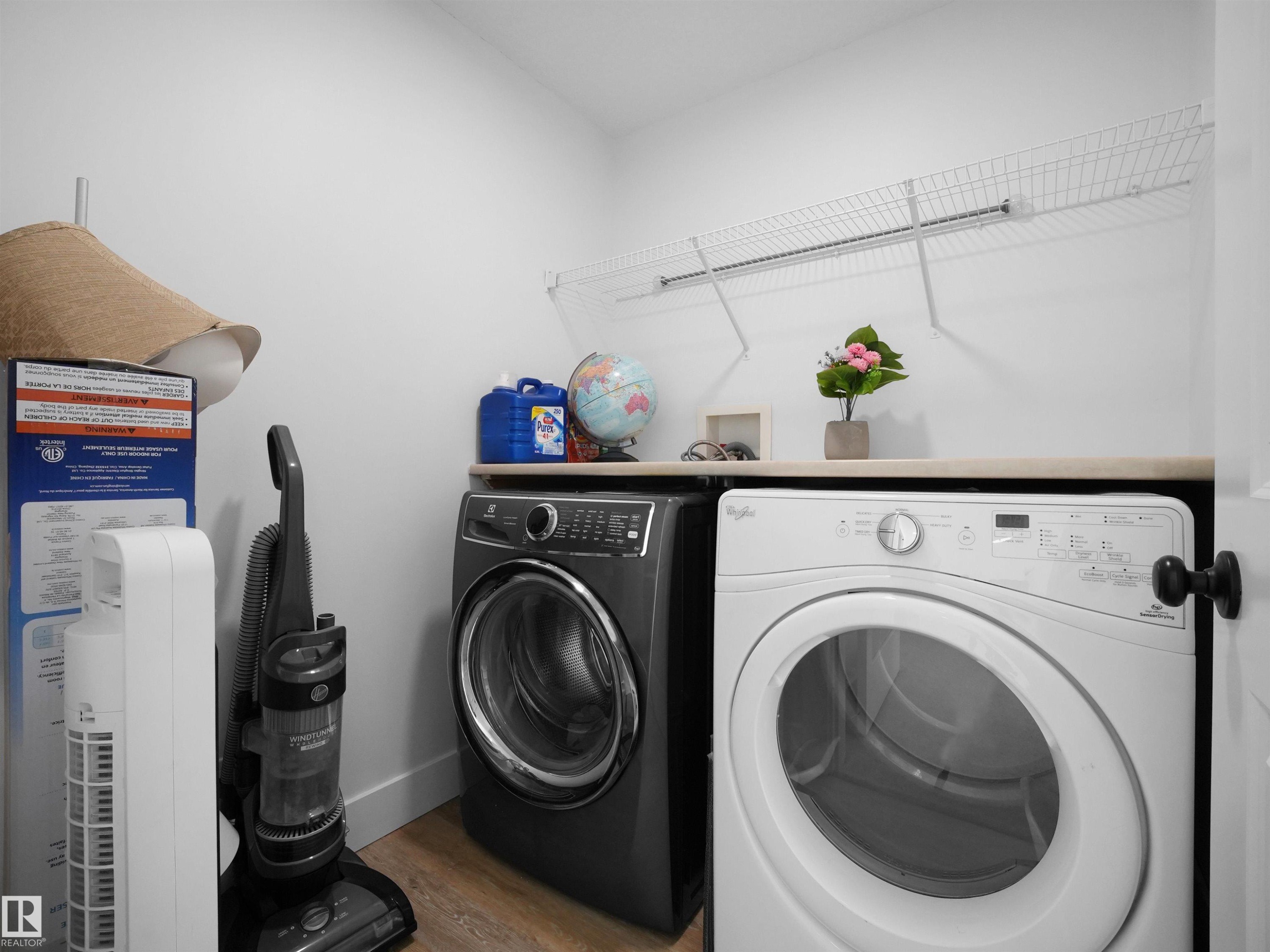 Laundry area featuring a side-by-side washer and dryer, a countertop surface, and wire shelving - 4231 Charles Close, Edmonton, AB - Indoor Photo Showing Laundry Room