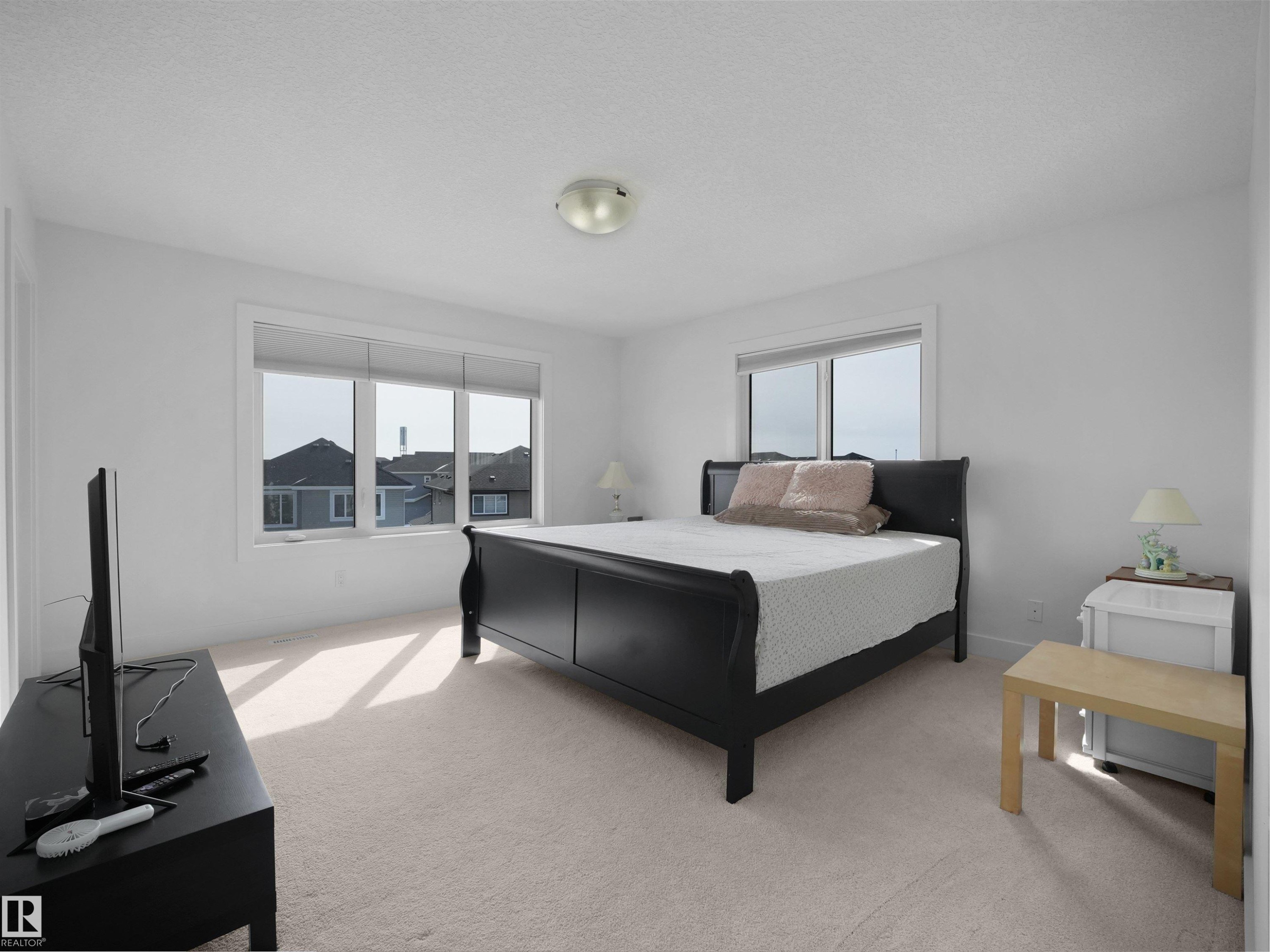 This room features light-colored carpeting, white walls, and two windows allowing natural light into the space - 4231 Charles Close, Edmonton, AB - Indoor Photo Showing Bedroom