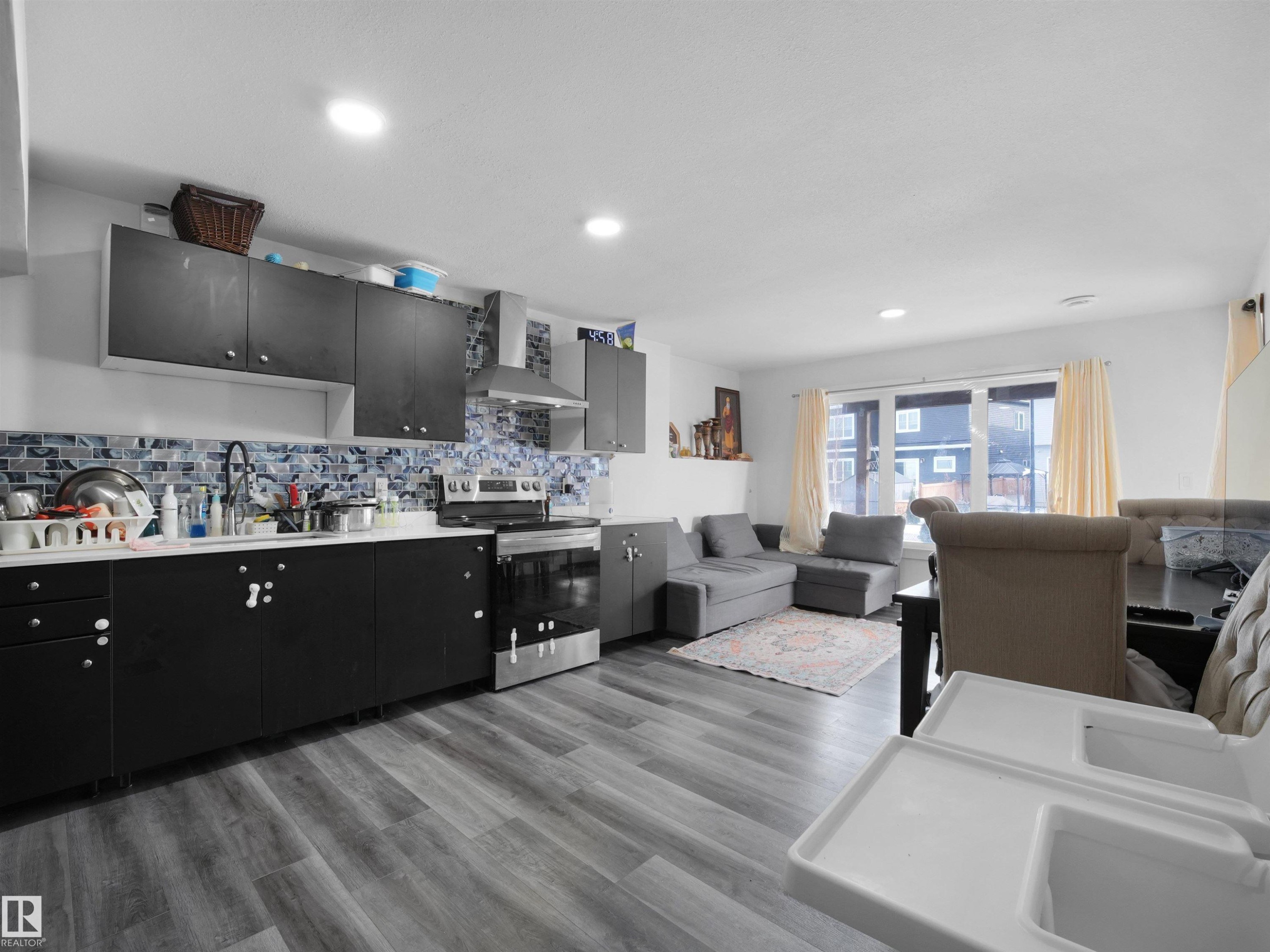 The property features an open concept kitchen and living area with wood-look flooring and recessed lighting - 4231 Charles Close, Edmonton, AB - Indoor Photo Showing Kitchen With Double Sink