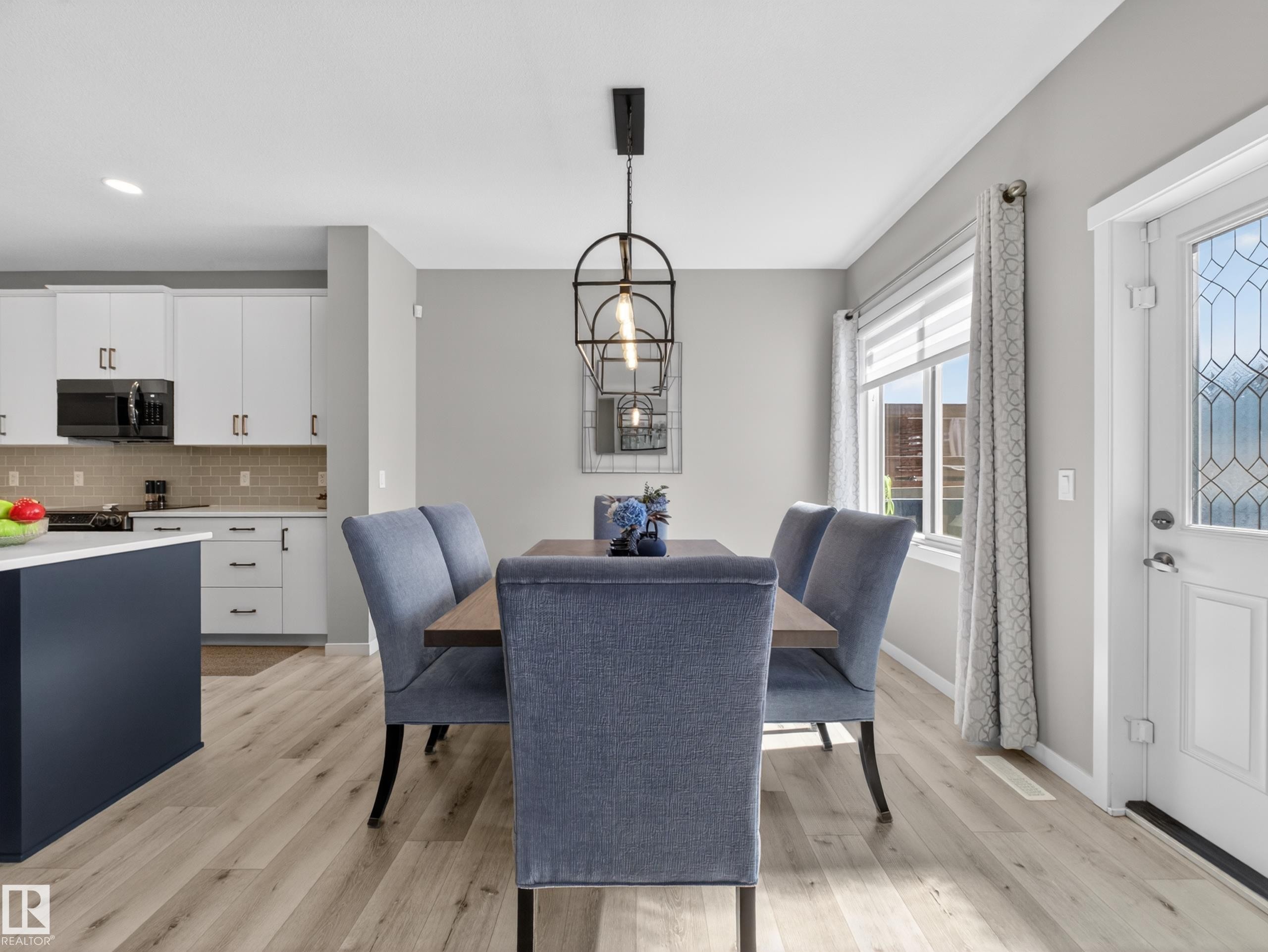 Dining area featuring light wood-finish flooring and a contemporary linear chandelier with exposed bulbs - 323 Balsam Link, Leduc, AB - Indoor