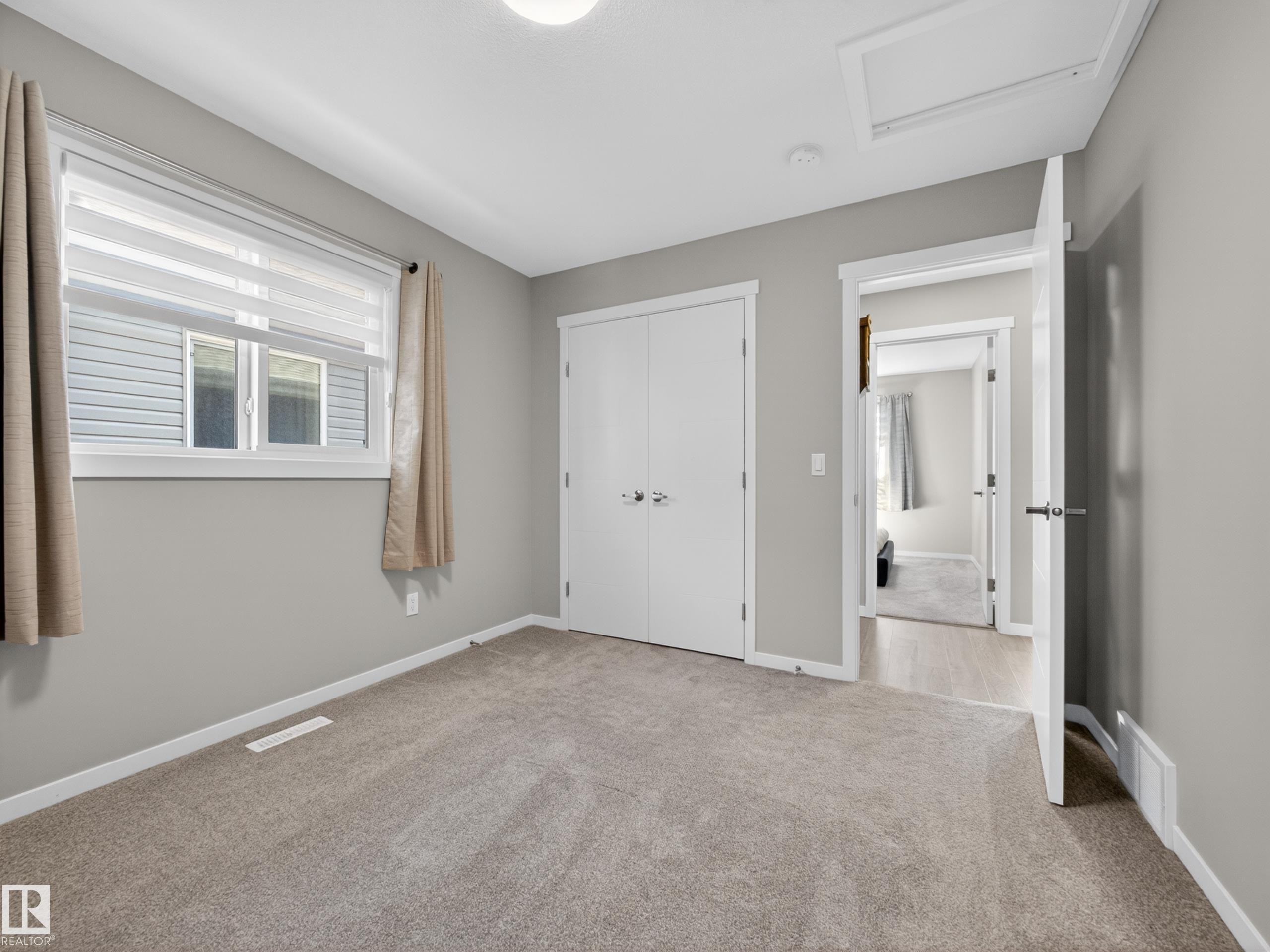 Carpeted room with a double-door closet, white trim, and a window featuring blinds - 323 Balsam Link, Leduc, AB - Indoor Photo Showing Other Room