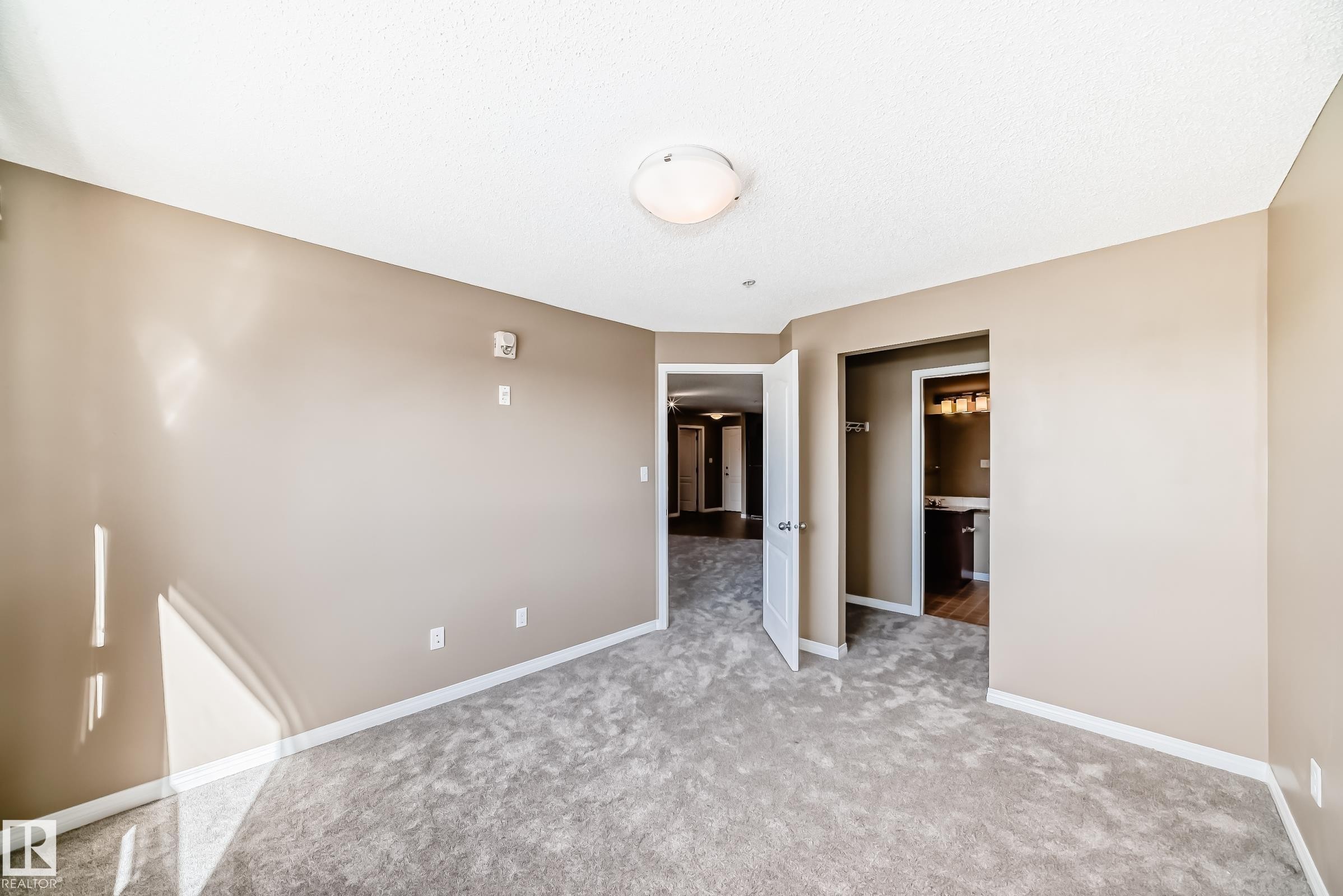 Spacious room featuring light tan walls and light gray carpeted flooring - 344 1520 Hammond Gate Gate, Edmonton, AB - Indoor Photo Showing Other Room