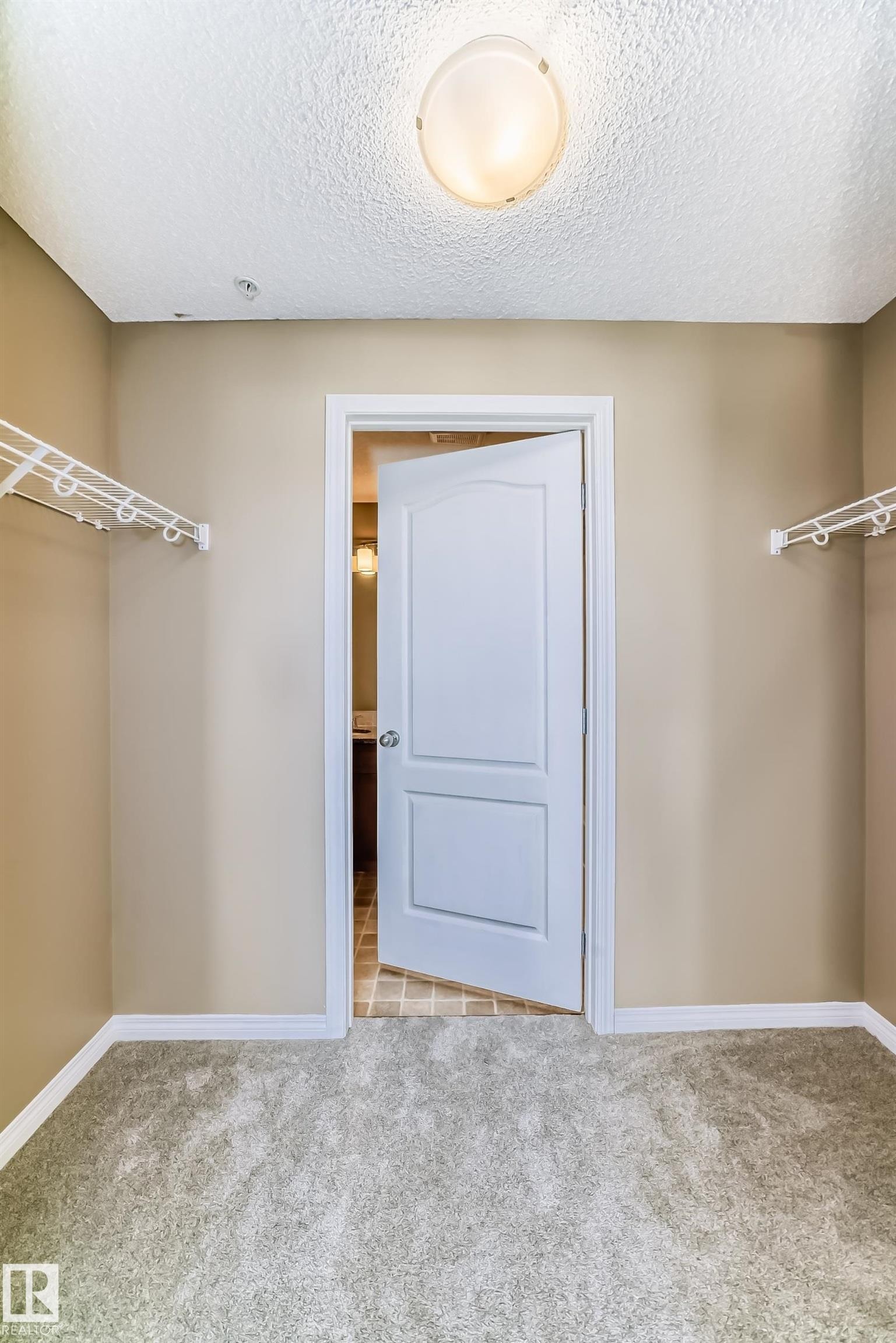 Spacious walk-in closet featuring light-colored carpeting, neutral painted walls, and built-in wire shelving systems - 344 1520 Hammond Gate Gate, Edmonton, AB - Indoor Photo Showing Other Room
