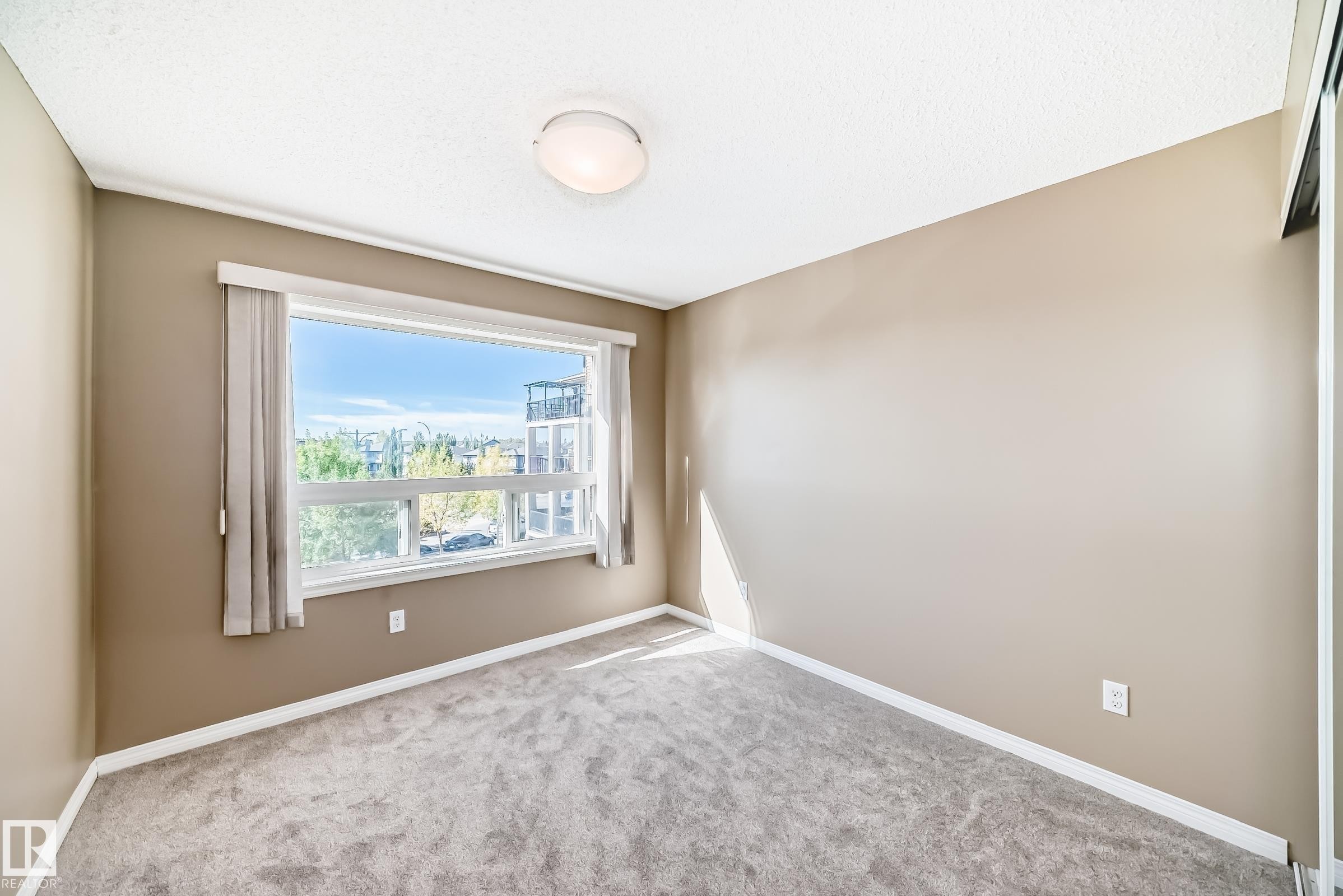 Room featuring neutral wall paint, light-colored carpeting, and a large window - 344 1520 Hammond Gate Gate, Edmonton, AB - Indoor Photo Showing Other Room