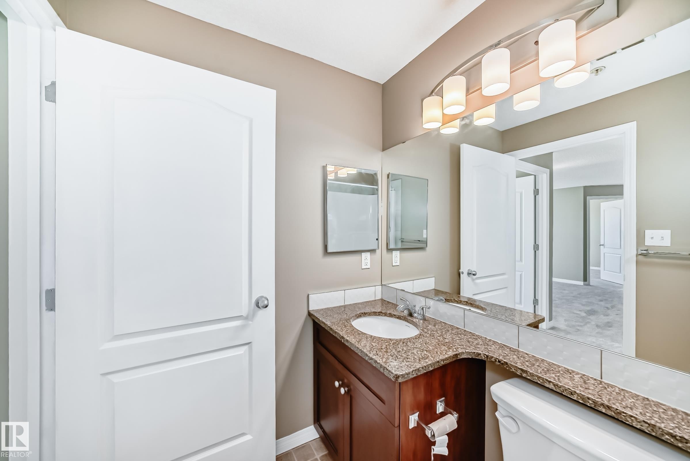 Vanity featuring an integrated sink, granite countertop, and dark wood-finish cabinetry - 344 1520 Hammond Gate Gate, Edmonton, AB - Indoor Photo Showing Bathroom