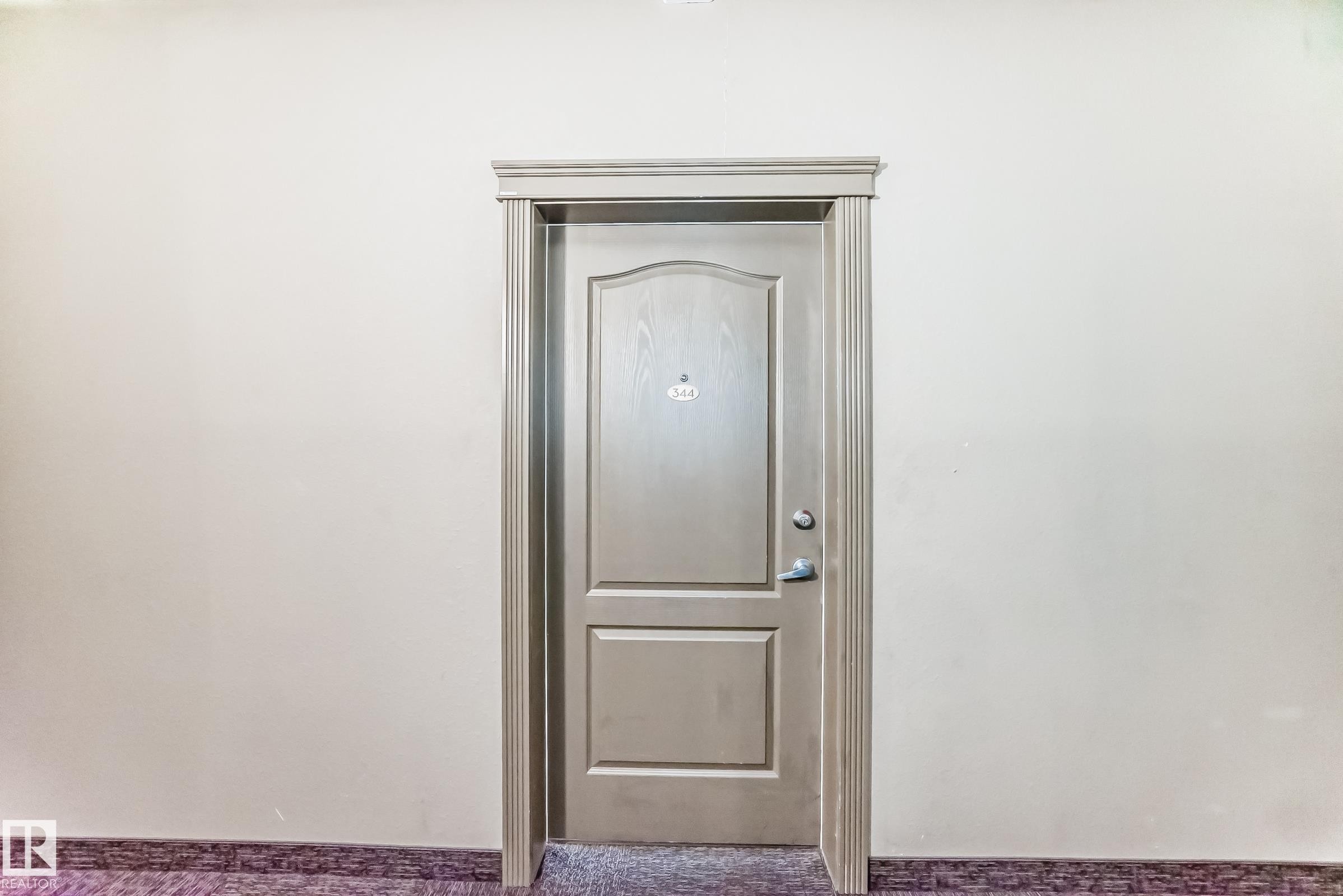 Panel-style interior door with detailed trimwork and a polished knob - 344 1520 Hammond Gate Gate, Edmonton, AB - Photo Showing Other Room
