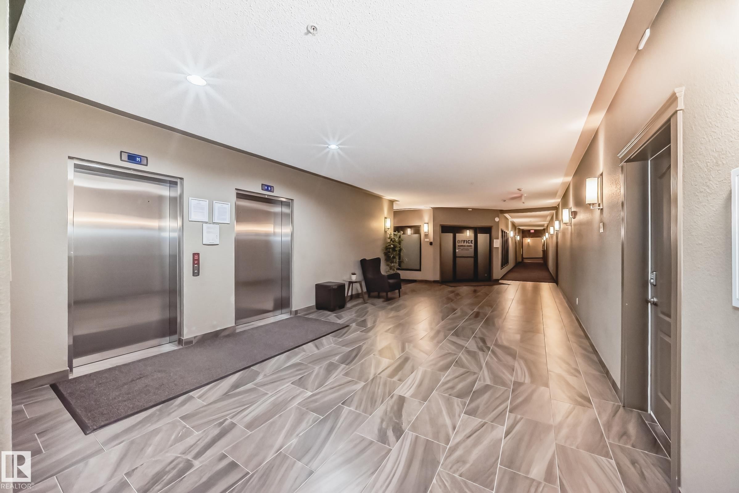 Hallway featuring two stainless steel elevators, overhead recessed lighting, and wall-mounted sconces - 344 1520 Hammond Gate Gate, Edmonton, AB - Indoor Photo Showing Other Room