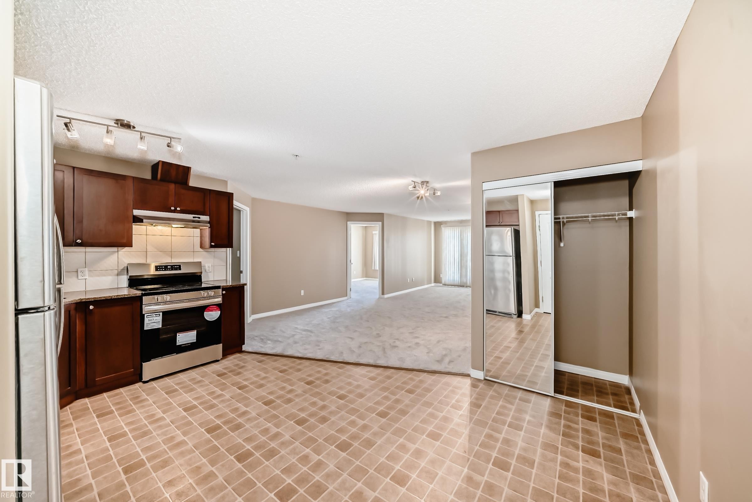 Kitchen featuring wood cabinetry, stainless steel appliances, track lighting, and a tiled backsplash - 344 1520 Hammond Gate Gate, Edmonton, AB - Indoor Photo Showing Kitchen