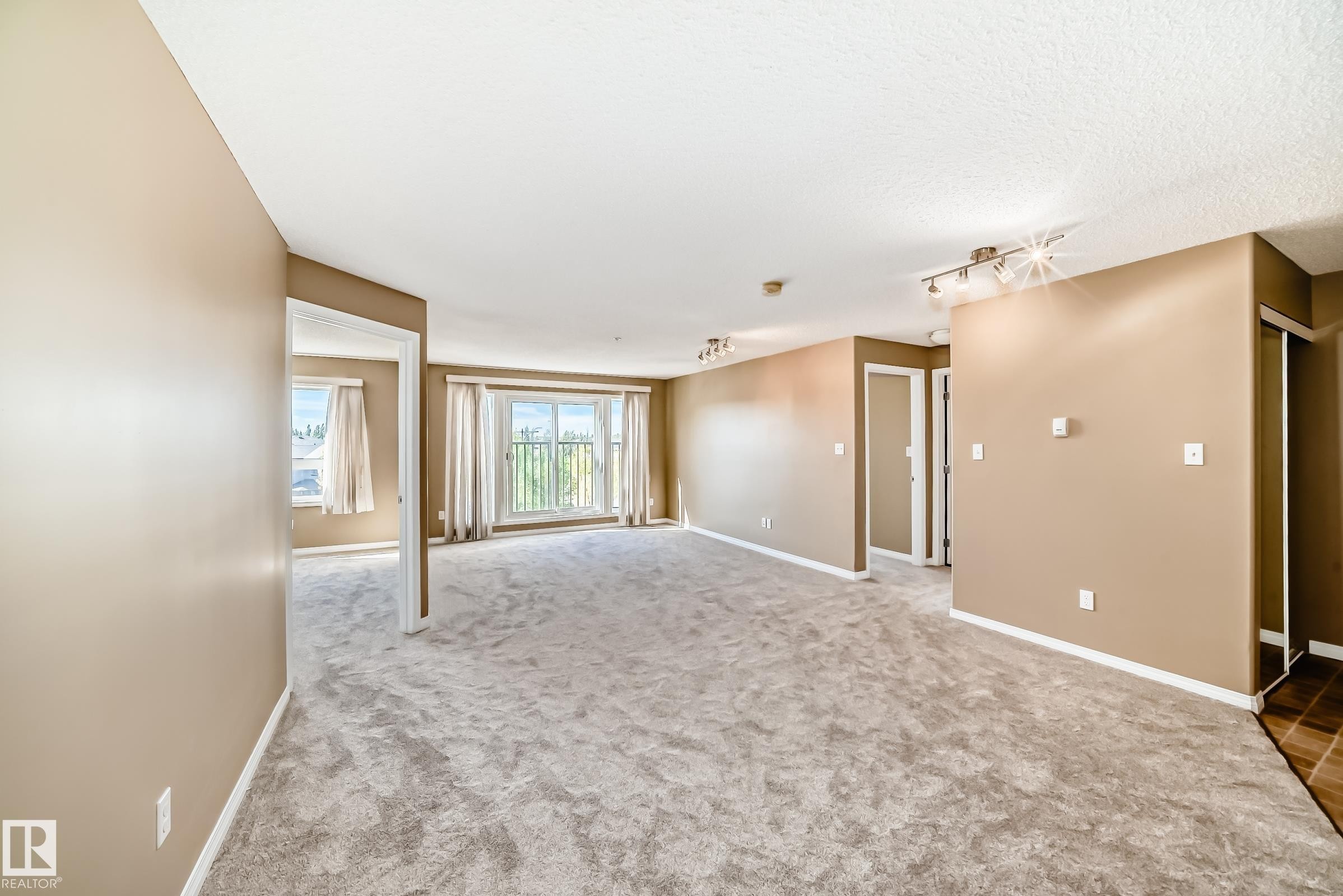 Spacious living area featuring light-toned carpeting and neutral wall paint - 344 1520 Hammond Gate Gate, Edmonton, AB - Indoor Photo Showing Other Room