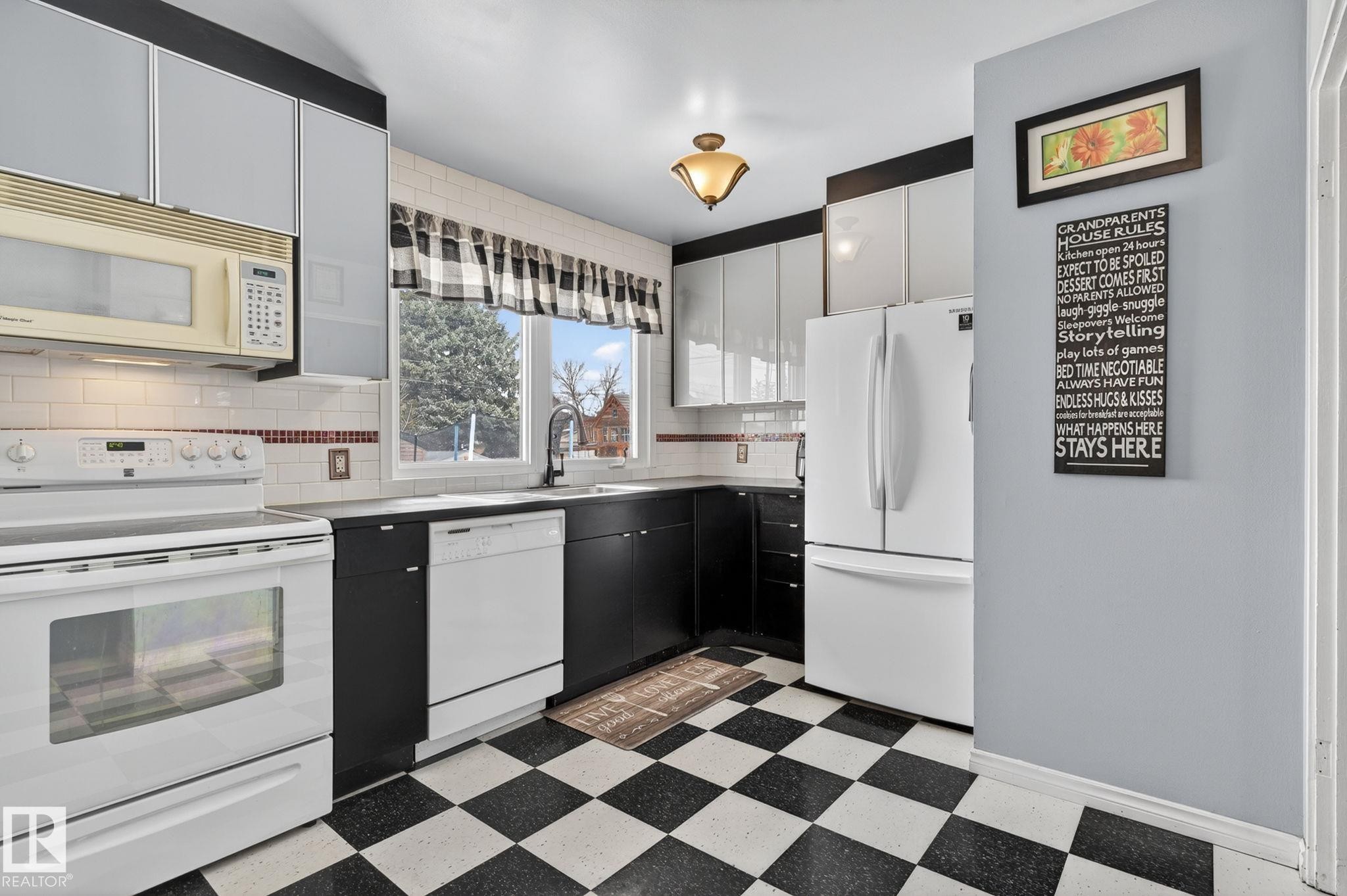 Kitchen featuring black and white checkerboard flooring, white subway tile backsplash, white appliances, and a built-in microwave - 9112 130 Avenue, Edmonton, AB - Indoor Photo Showing Kitchen