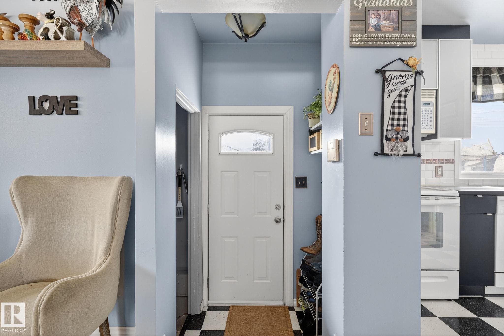 Entryway featuring a white paneled door with an arched glass insert, black and white checkered flooring, a light blue wall finish, and overhead lighting - 9112 130 Avenue, Edmonton, AB - Indoor Photo Showing Other Room