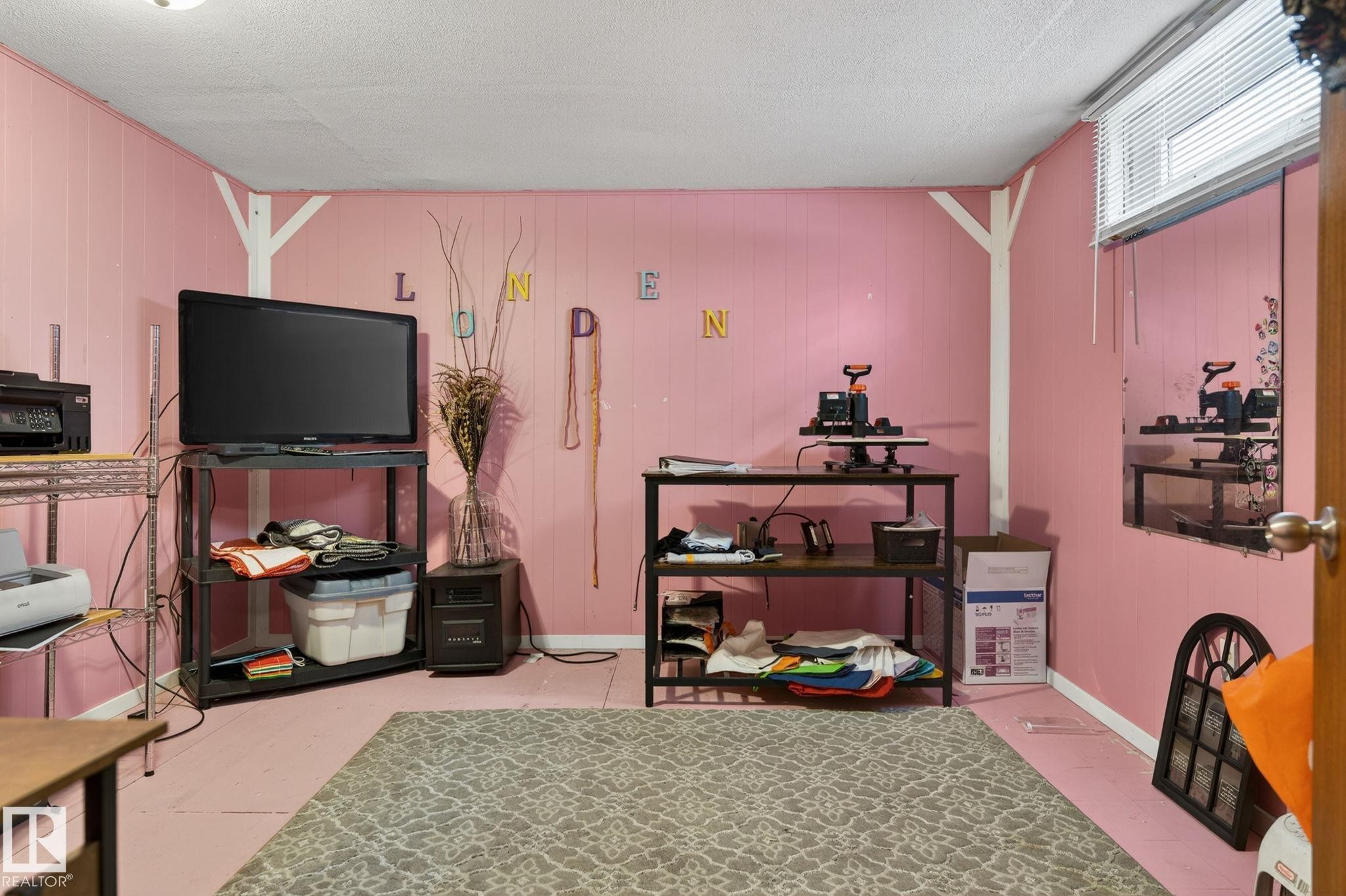 Room featuring vertical paneling, painted flooring, white trim, and a high-set window with blinds - 9112 130 Avenue, Edmonton, AB - Indoor