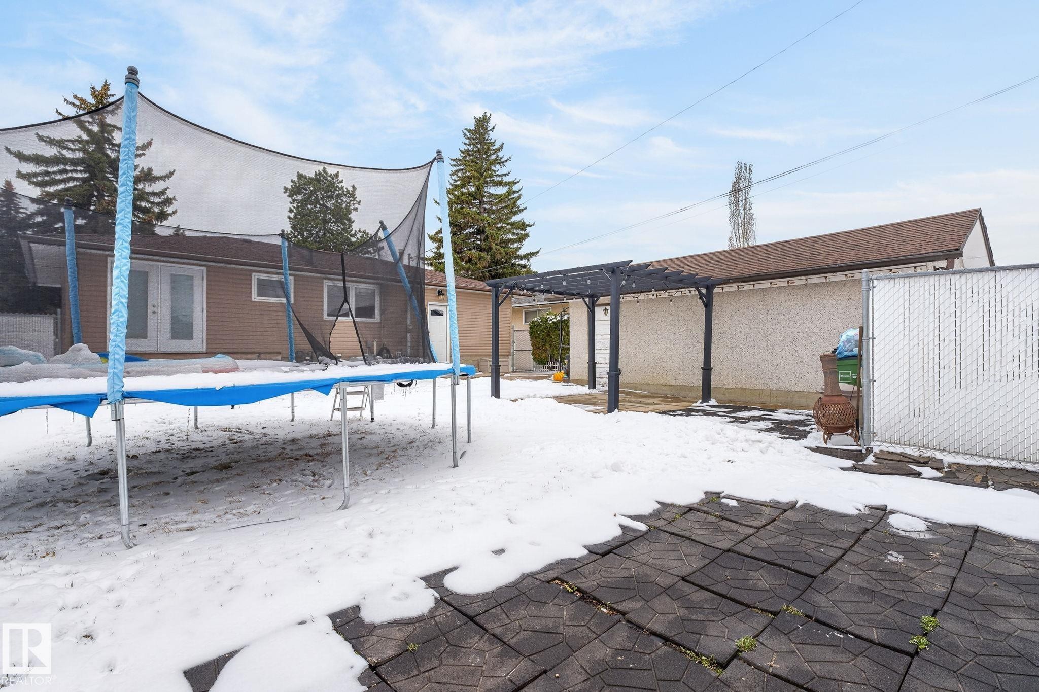 Expansive rear yard featuring a paved patio area, a pergola structure, and a chain-link fence - 9112 130 Avenue, Edmonton, AB - Outdoor