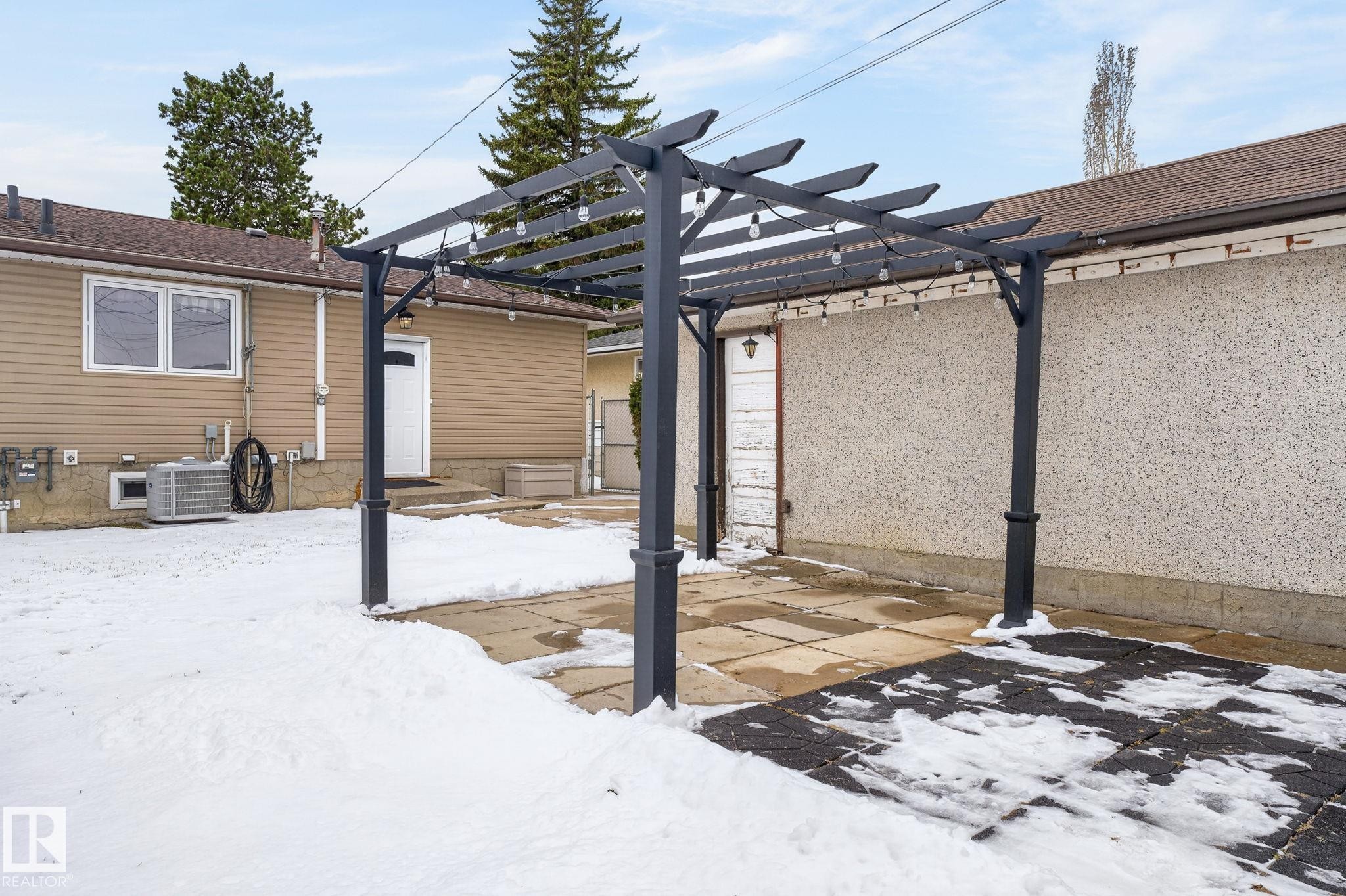 Outdoor pergola structure with string lighting, concrete patio, and visible exterior wall with stucco finish - 9112 130 Avenue, Edmonton, AB - Outdoor