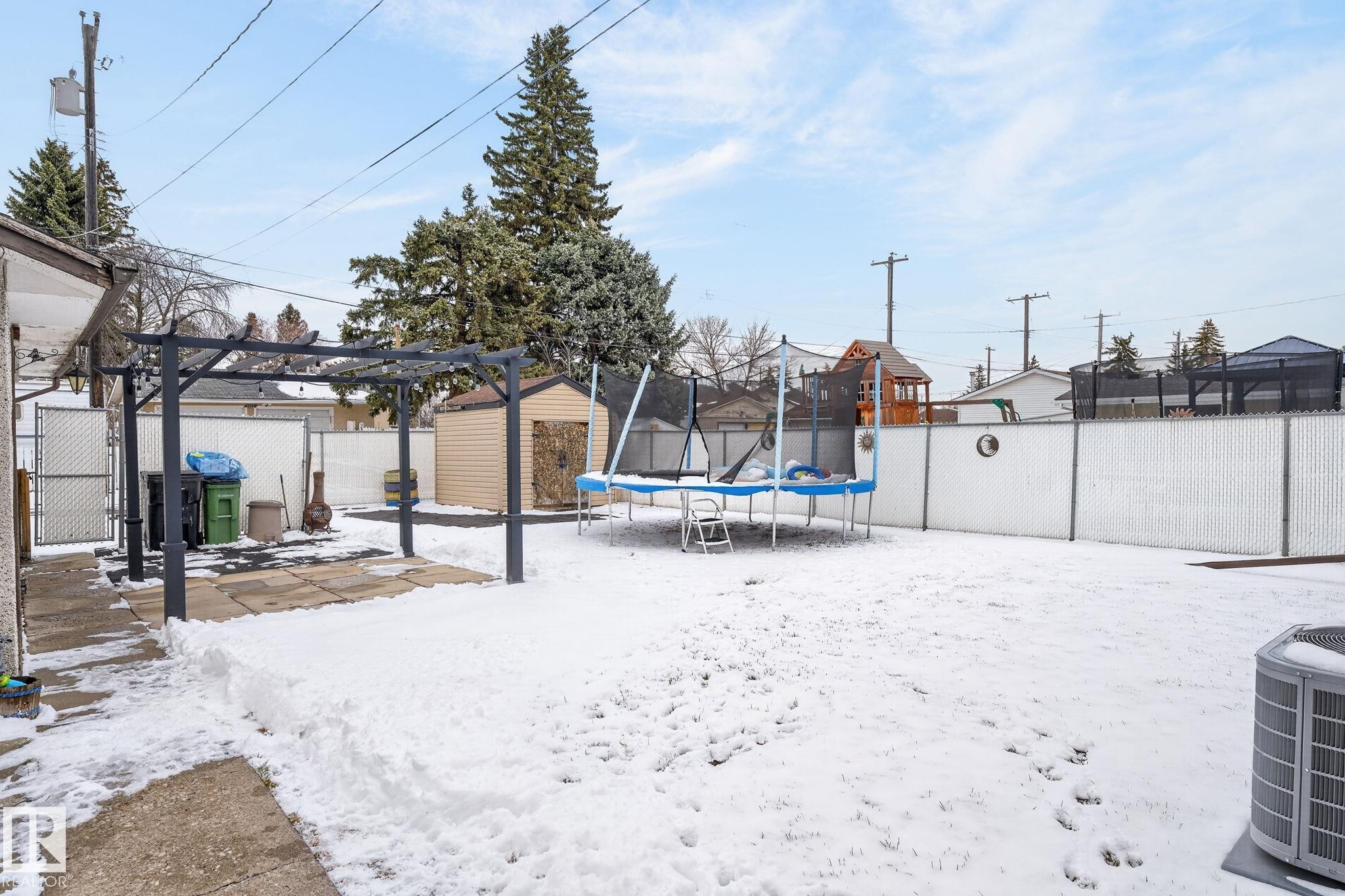 Expansive backyard featuring a pergola-covered patio with concrete pavers, a chain-link fence, and a utility shed - 9112 130 Avenue, Edmonton, AB - Outdoor