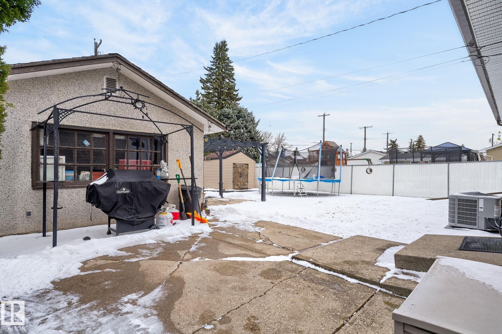 Expansive backyard featuring a concrete patio, white privacy fencing, and a storage shed - 9112 130 Avenue, Edmonton, AB - Outdoor