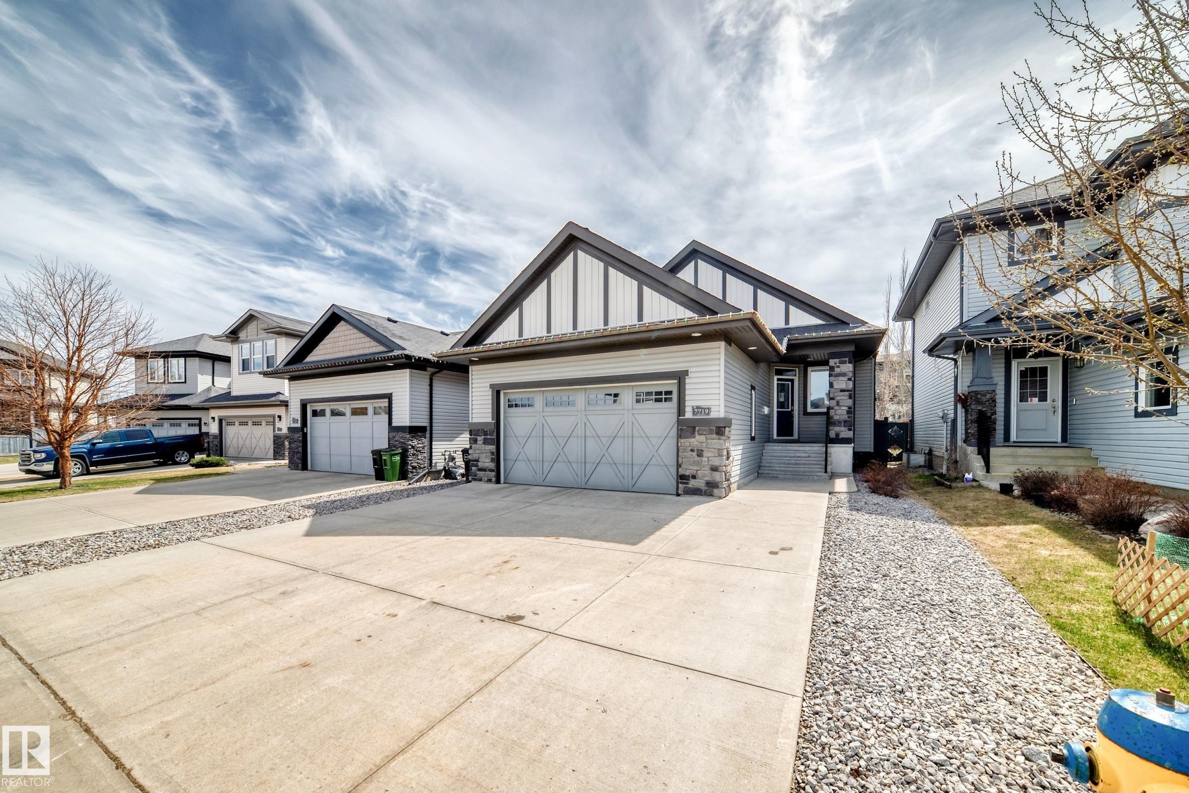 Contemporary exterior featuring light gray siding with dark trim accents - 7719 Getty Wynd, Edmonton, AB