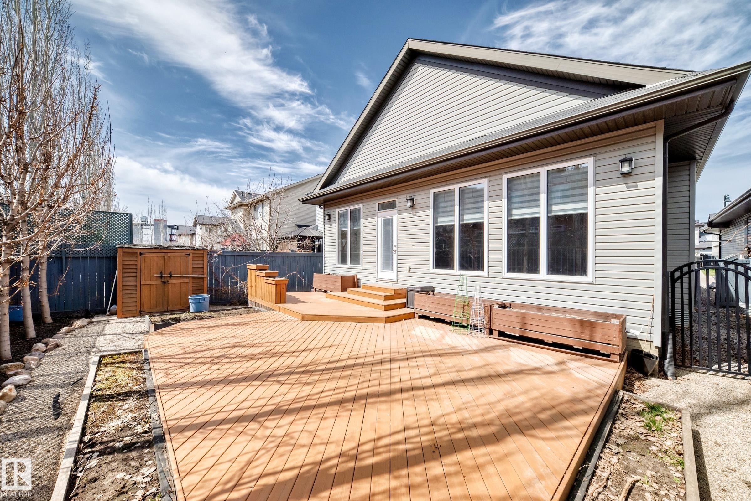 Expansive multi-level wood deck featuring integrated planters and direct access to the interior - 7719 Getty Wynd, Edmonton, AB