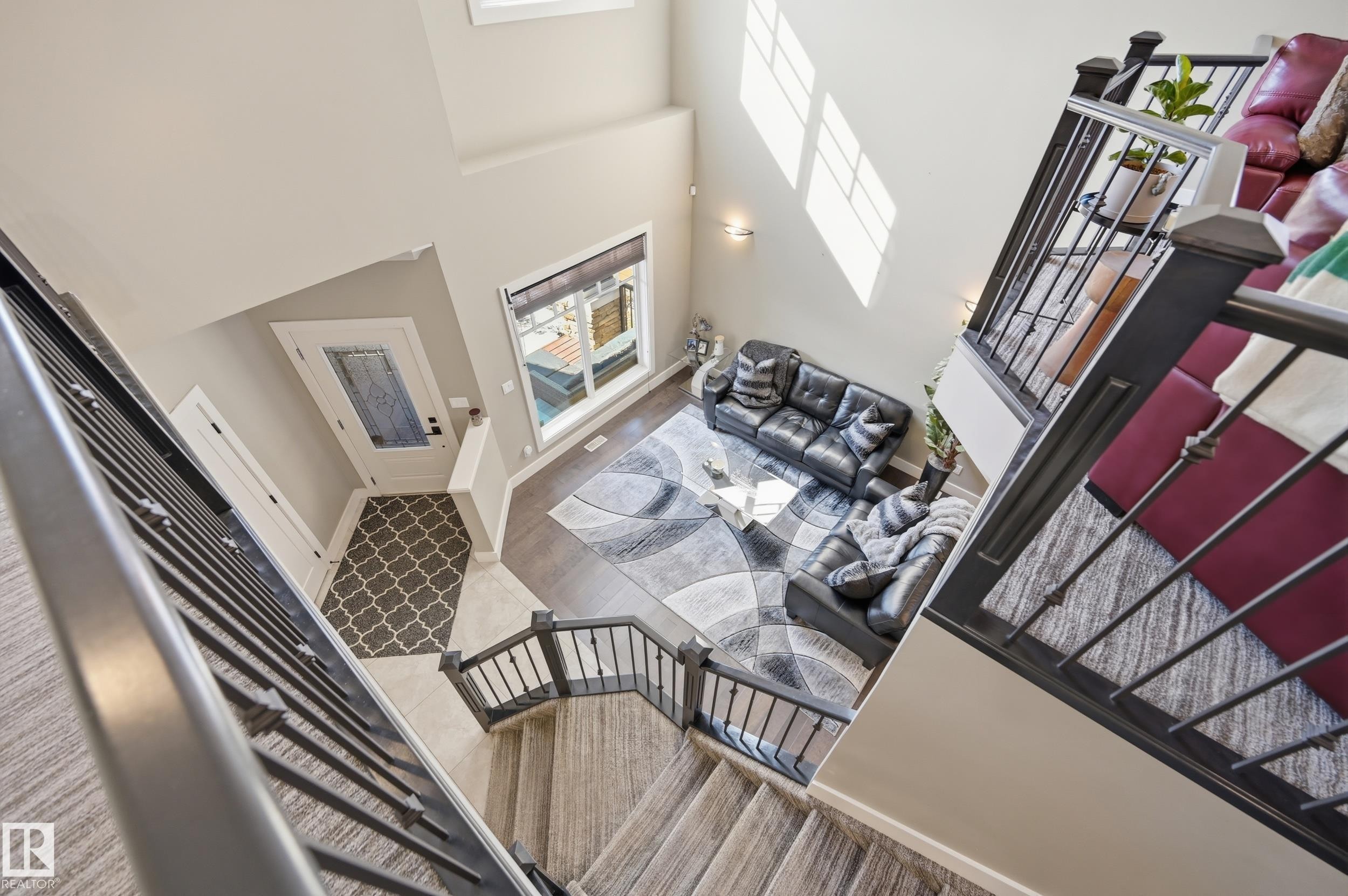 This property features an inviting entryway with patterned floor tiles, leading into a living area with hardwood flooring - 2018 Armitage Green, Edmonton, AB - Indoor Photo Showing Other Room With Fireplace