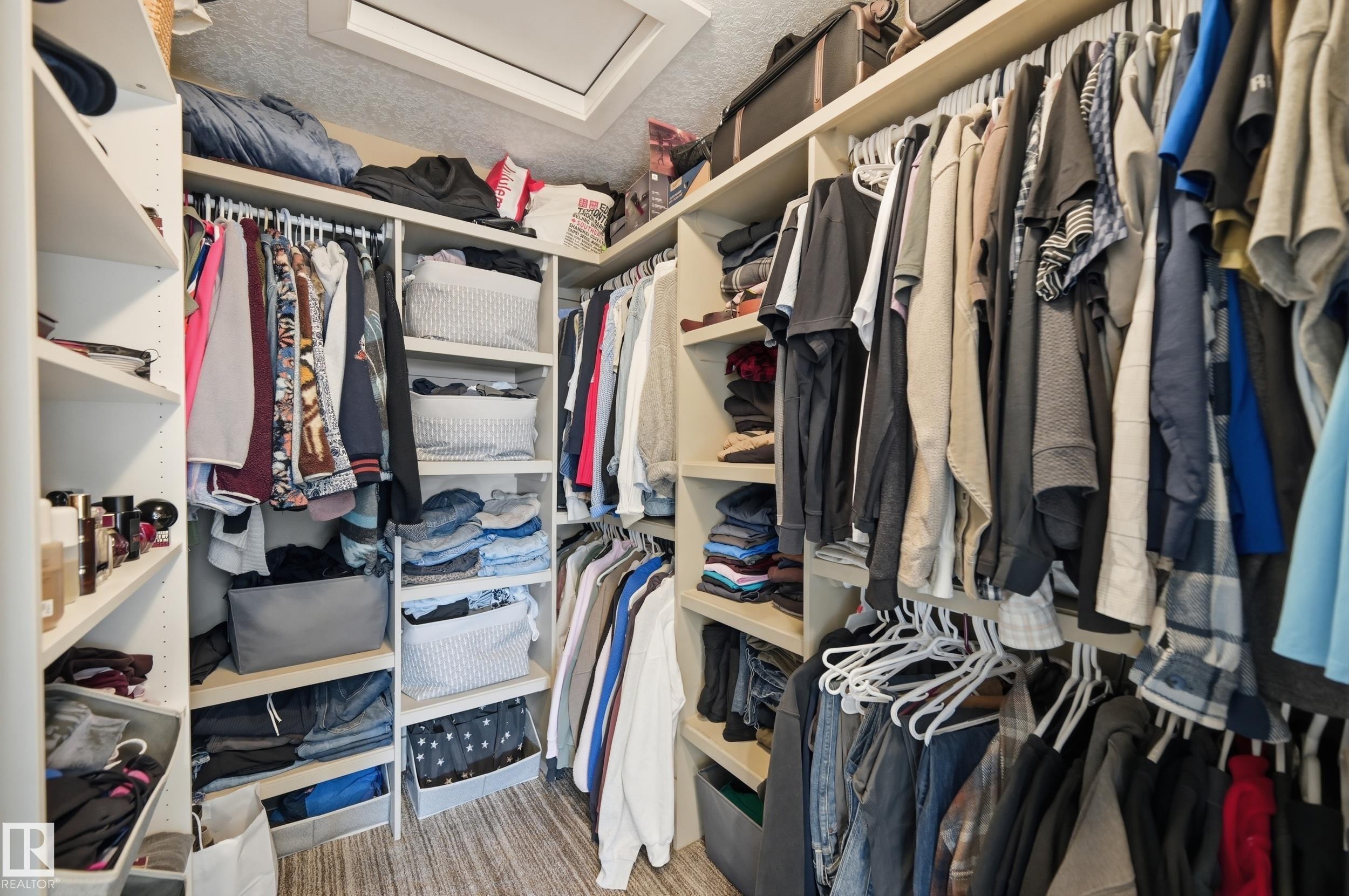 Walk-in closet featuring extensive built-in shelving, hanging rods, and a skylight - 2018 Armitage Green, Edmonton, AB - Indoor With Storage