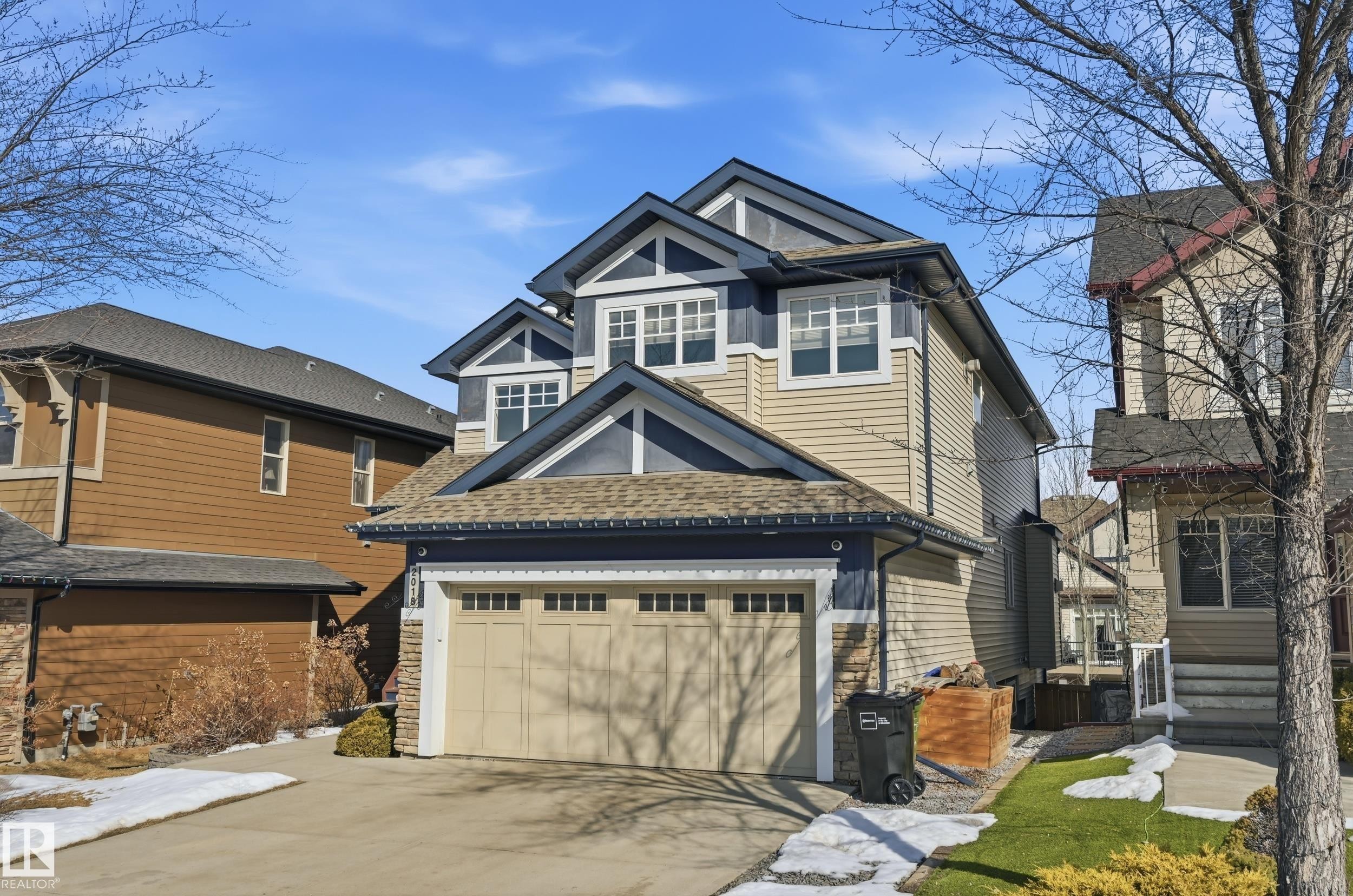This property features a two-car garage, a paved driveway, and stone accents on the exterior - 2018 Armitage Green, Edmonton, AB - Outdoor