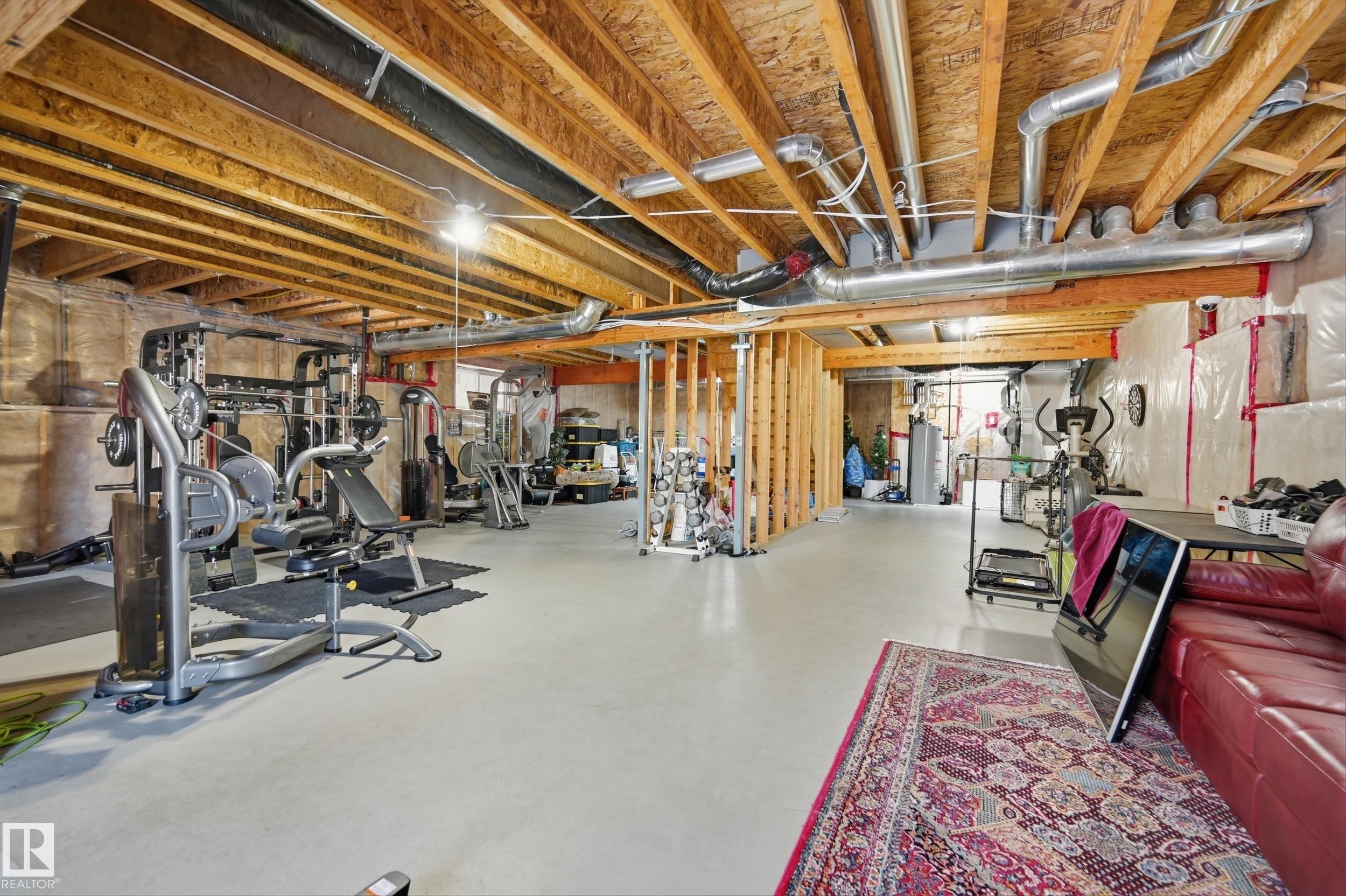 Spacious unfinished basement with exposed wooden beams and ductwork, featuring a painted concrete floor - 2018 Armitage Green, Edmonton, AB - Indoor Photo Showing Basement