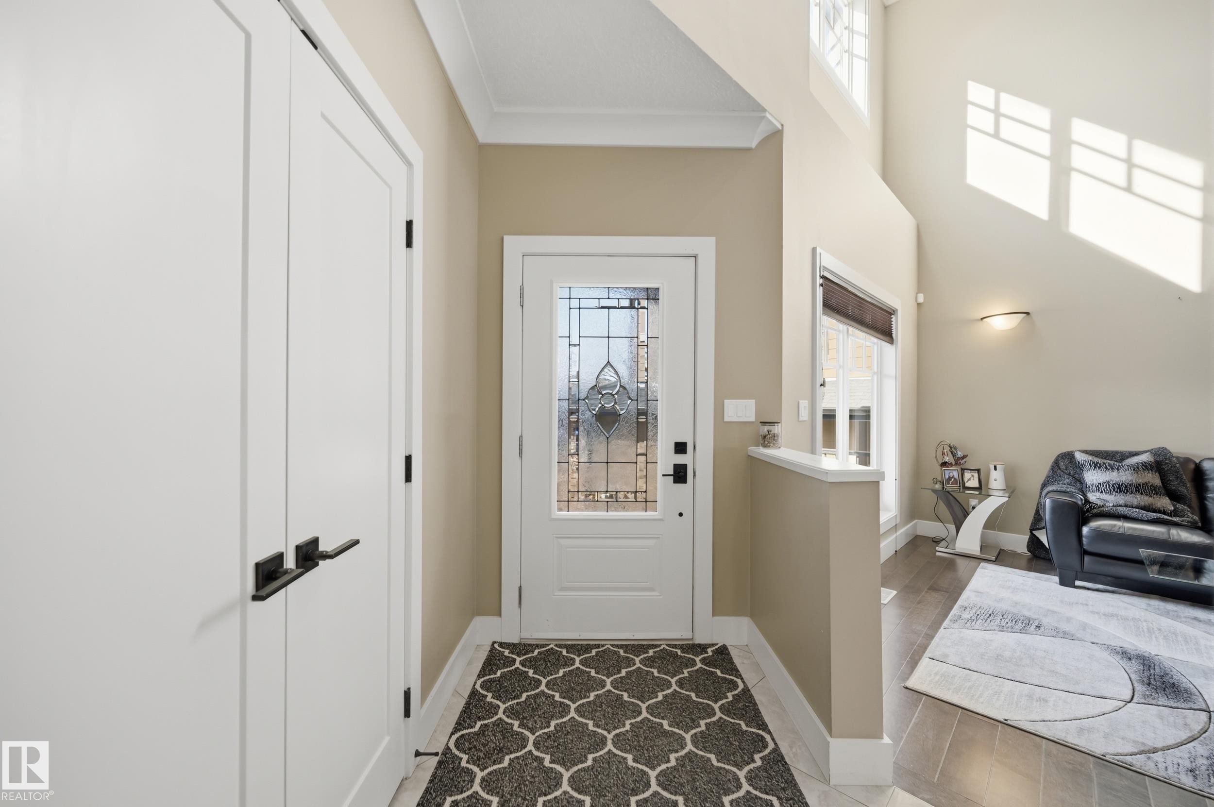 The property features a welcoming entryway with a decorative glass front door, two white doors with black hardware, and a high ceiling - 2018 Armitage Green, Edmonton, AB - Indoor Photo Showing Other Room