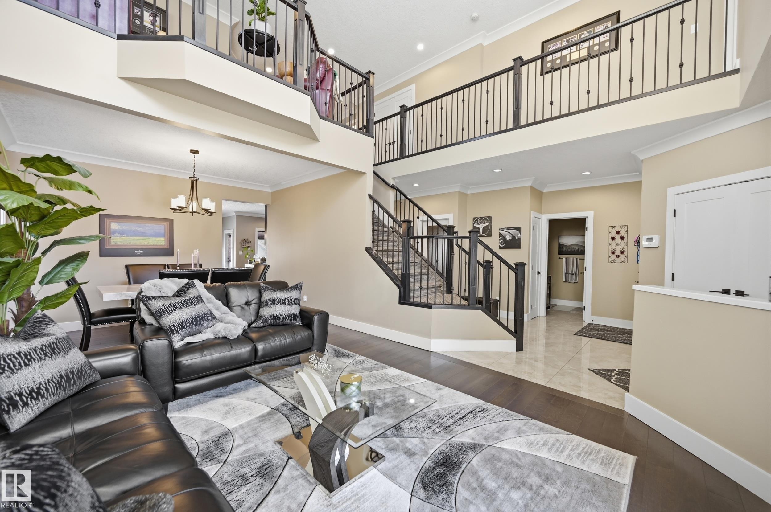 This property features an open-concept living space with hardwood flooring, a dining area with a chandelier, and a second-story landing with an open railing - 2018 Armitage Green, Edmonton, AB - Indoor