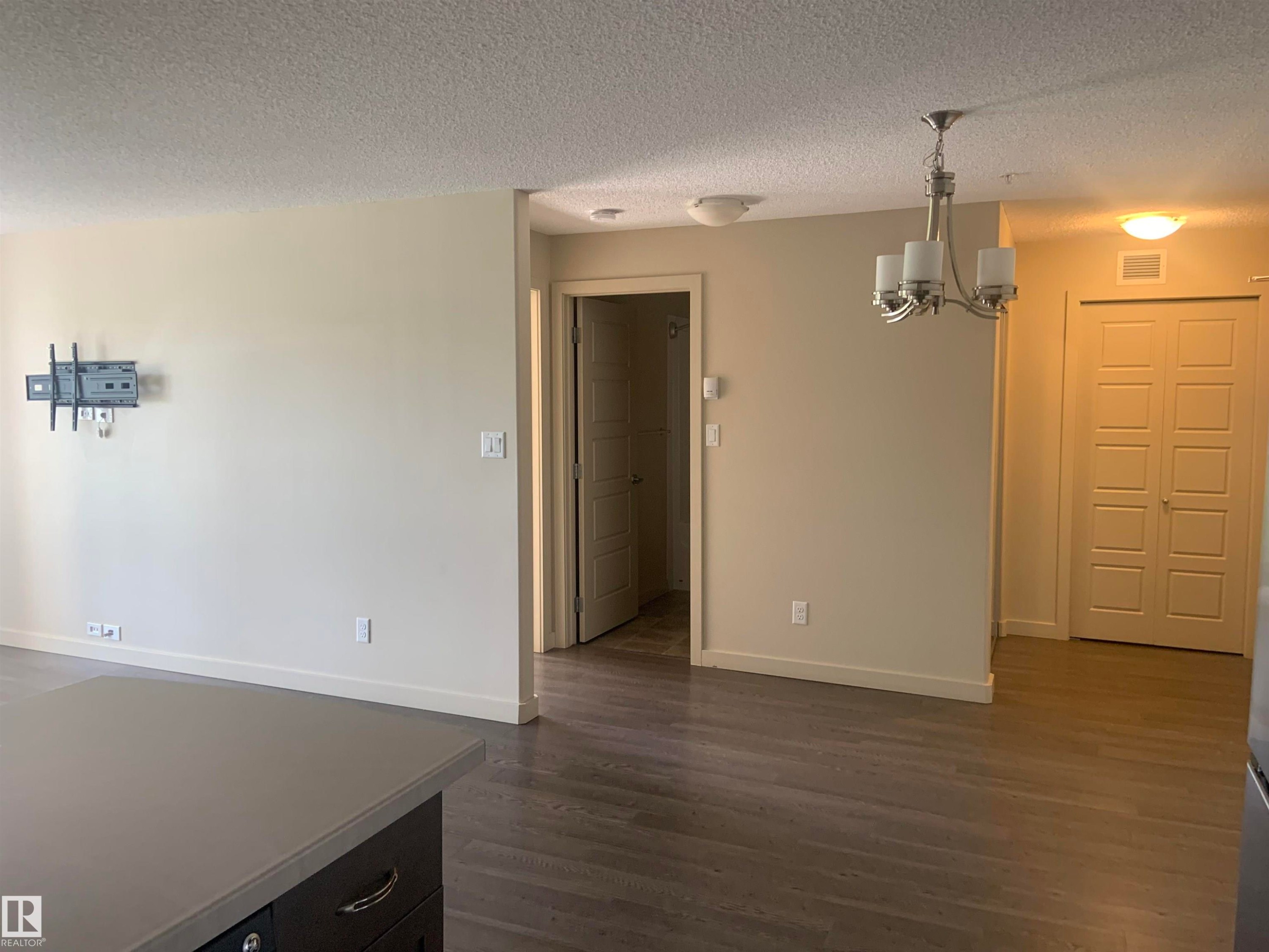 Open concept interior featuring wood-finish flooring and neutral wall tones - 307 6084 Stanton Drive, Edmonton, AB - Indoor Photo Showing Other Room
