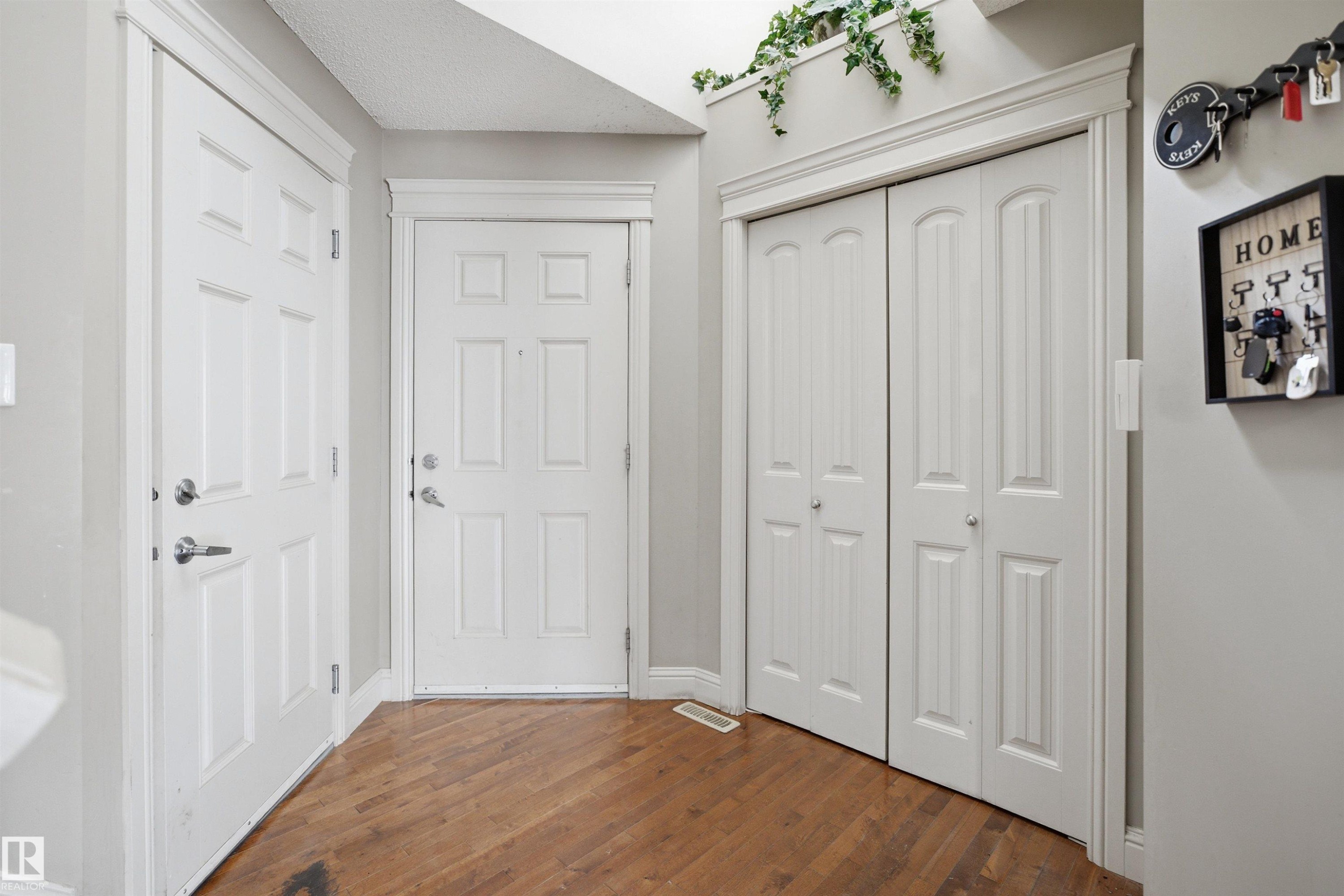 Entryway featuring wood-finish flooring, white paneled doors, bi-fold closet doors, and light gray wall paint - 3533 11 Street, Edmonton, AB