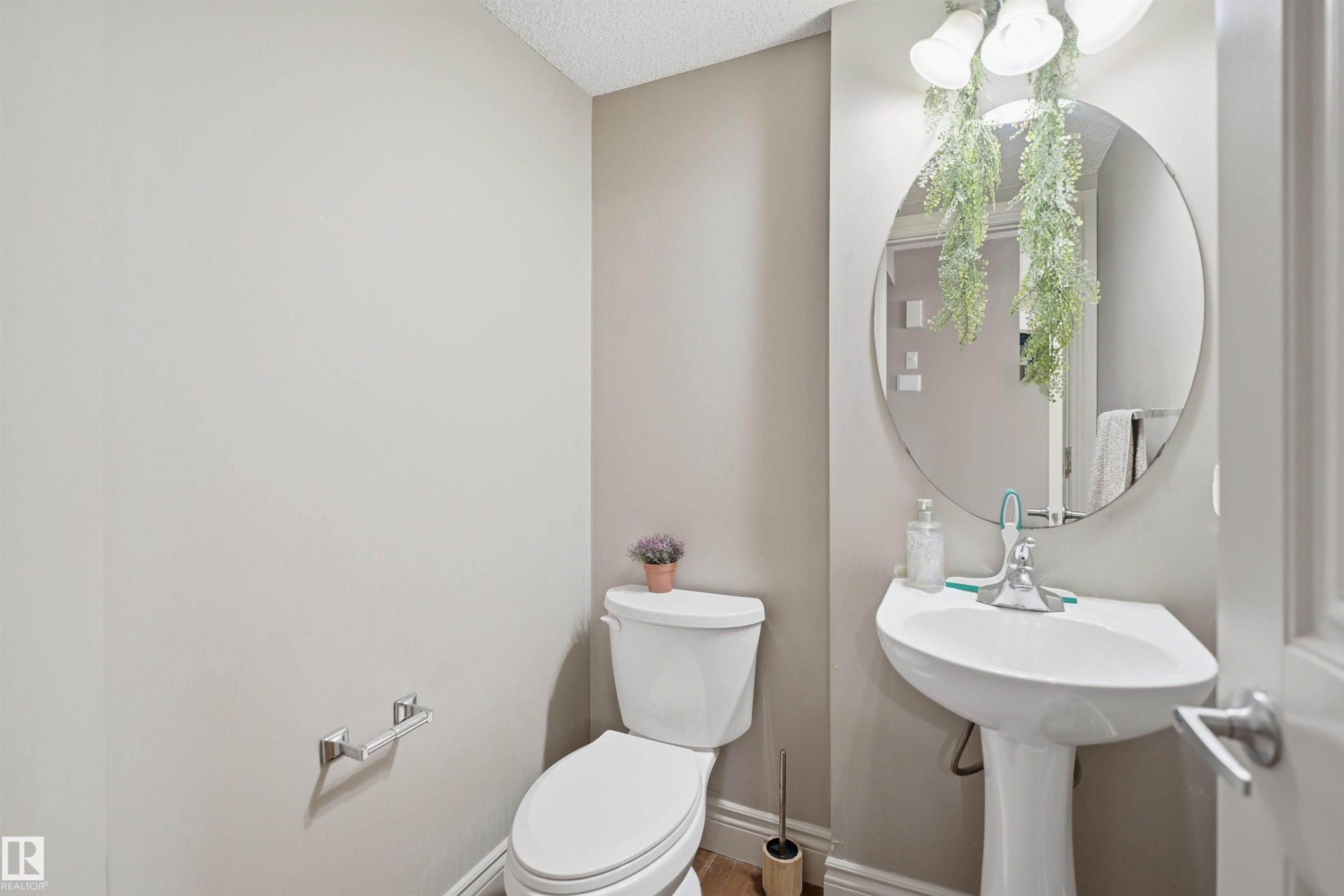 Pedestal sink with chrome fixtures and a circular mirror - 3533 11 Street, Edmonton, AB