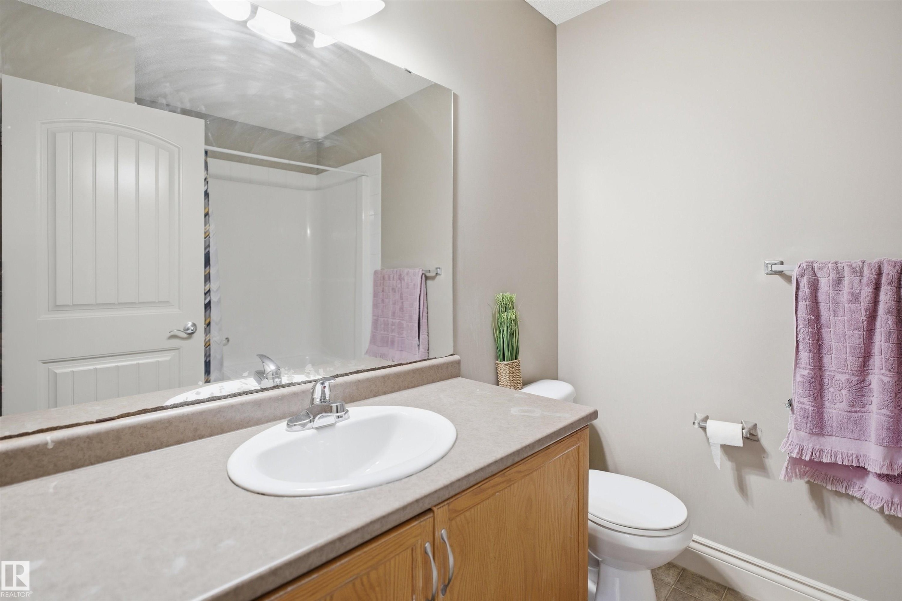 Bathroom featuring a wood-finish vanity with an integrated sink and laminate countertop - 3533 11 Street, Edmonton, AB