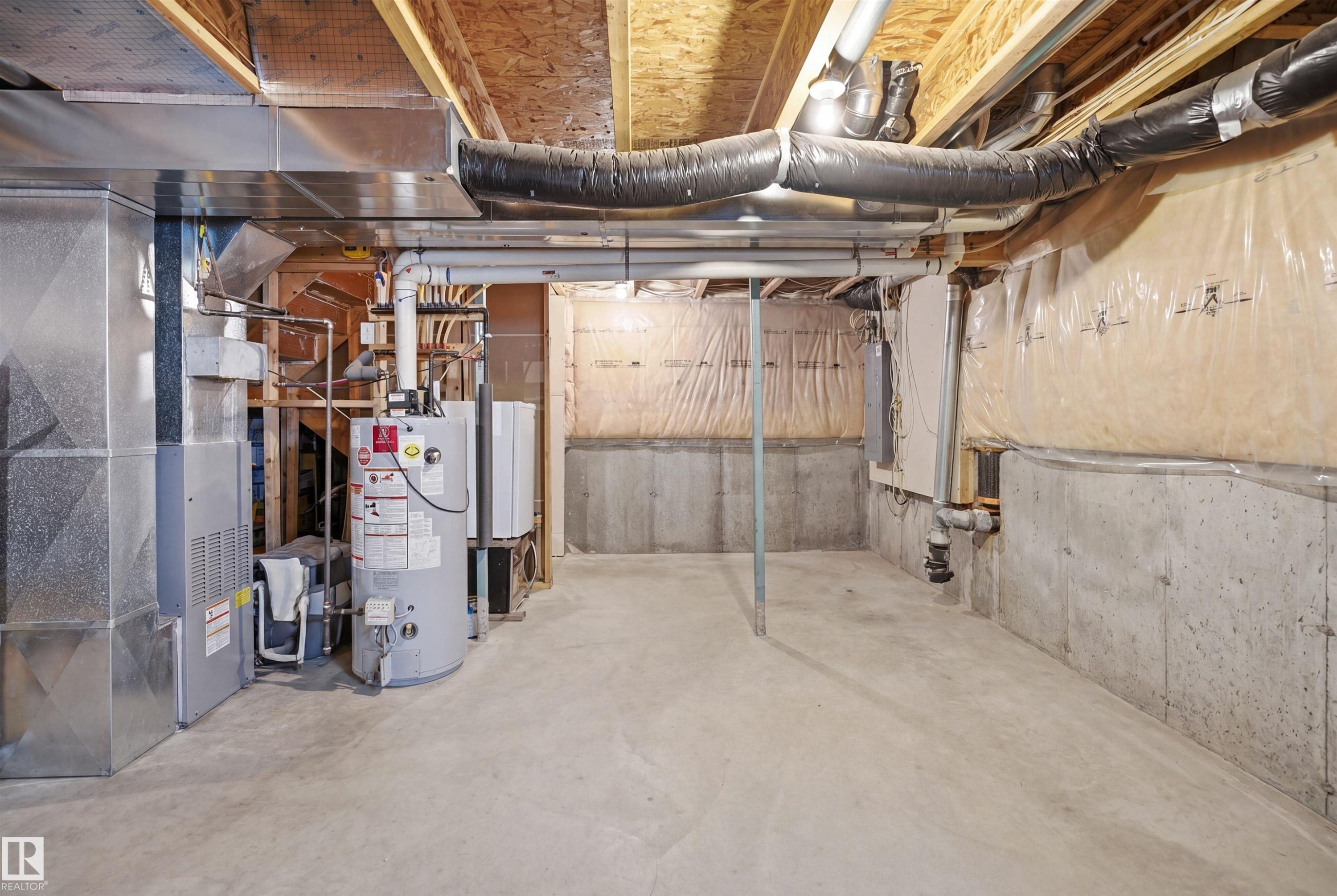 Unfinished basement space featuring concrete flooring, exposed wood joists, and concrete foundation walls - 3533 11 Street, Edmonton, AB