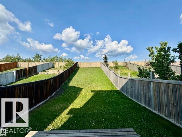 Expansive backyard featuring a sloped lawn, mature trees, and privacy fencing - 3533 11 Street, Edmonton, AB