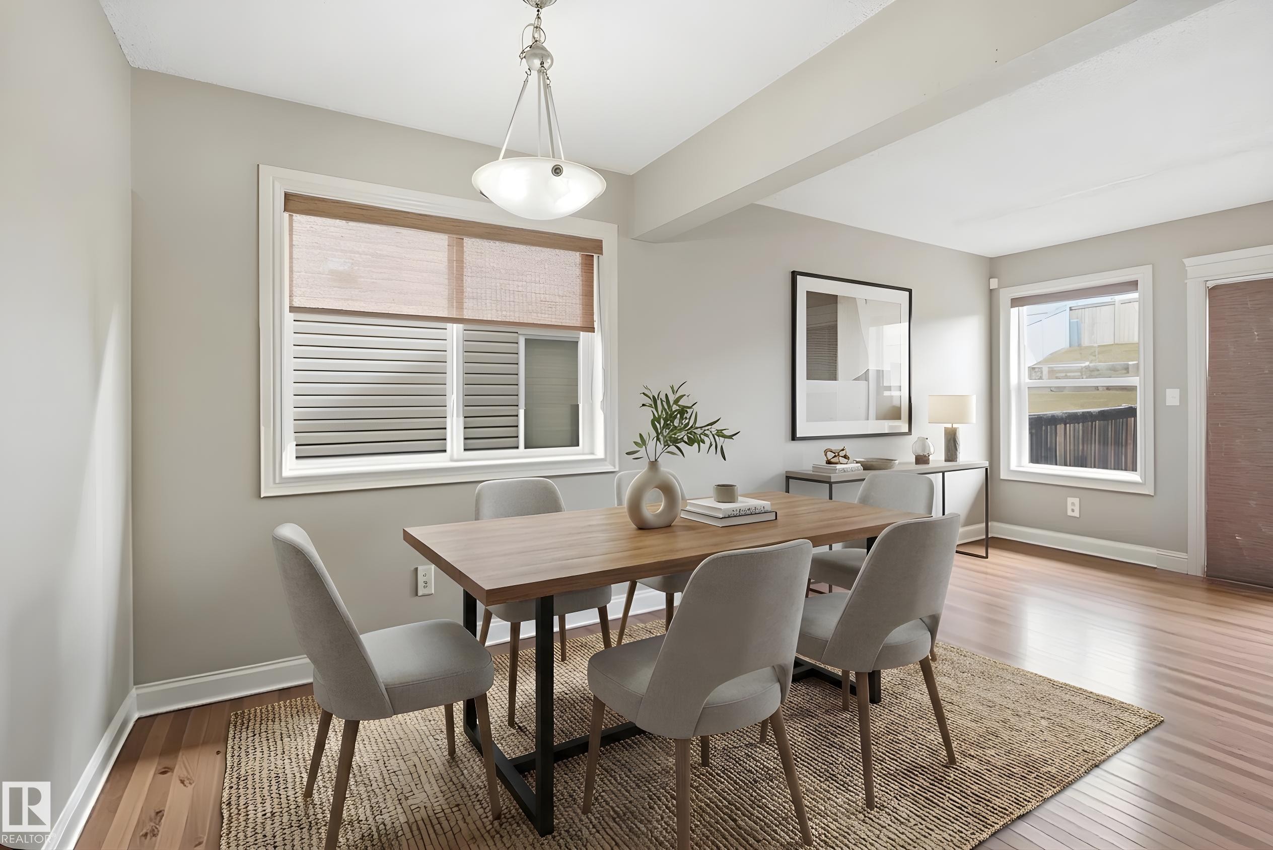 Light-filled dining area featuring wood-finish flooring, a contemporary chandelier, and multiple windows with woven shades - 3533 11 Street, Edmonton, AB