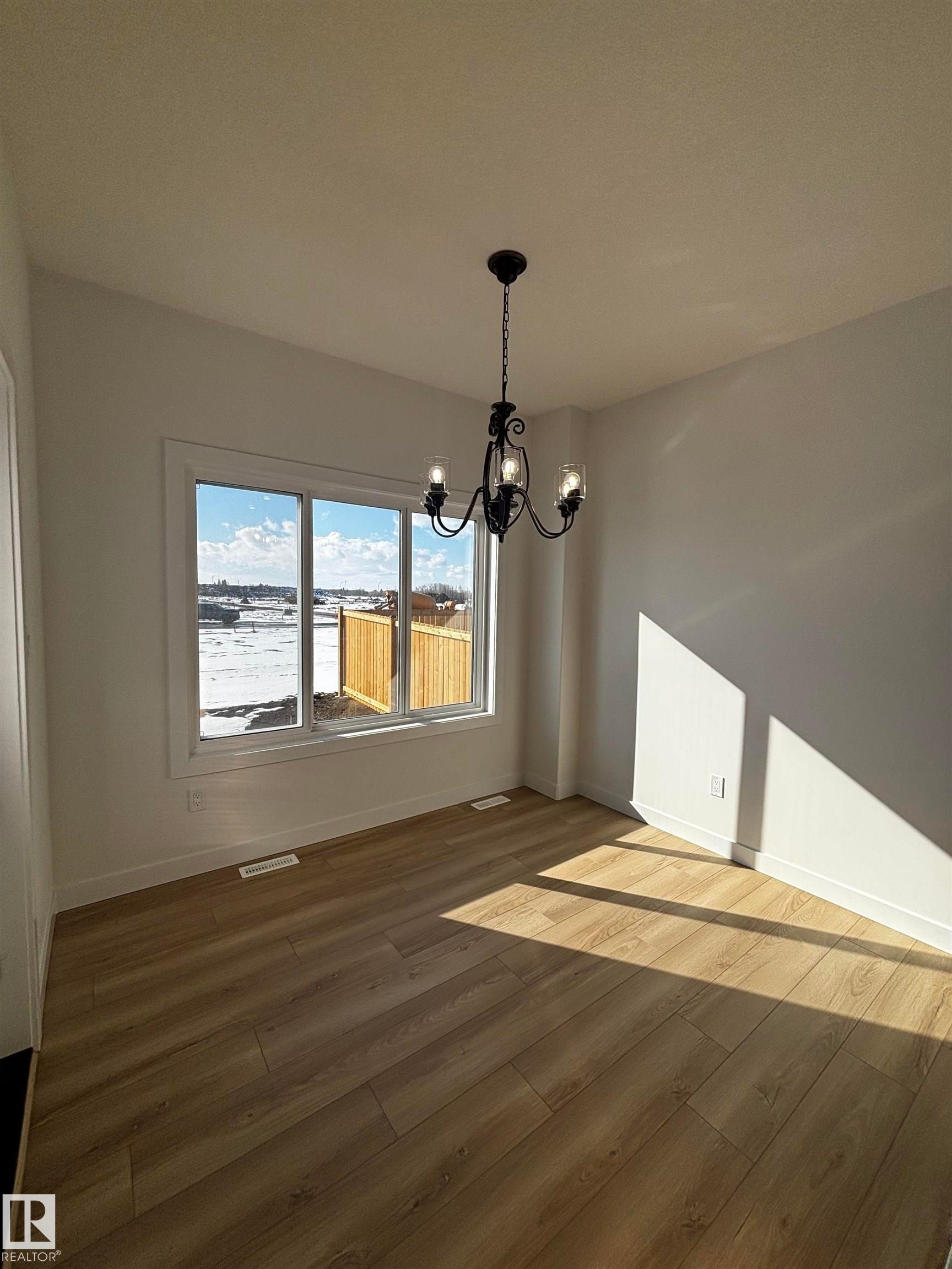 This bright room features a large window, a classic chandelier, and light-toned flooring - 2012 210 St, Edmonton, AB - Indoor Photo Showing Other Room