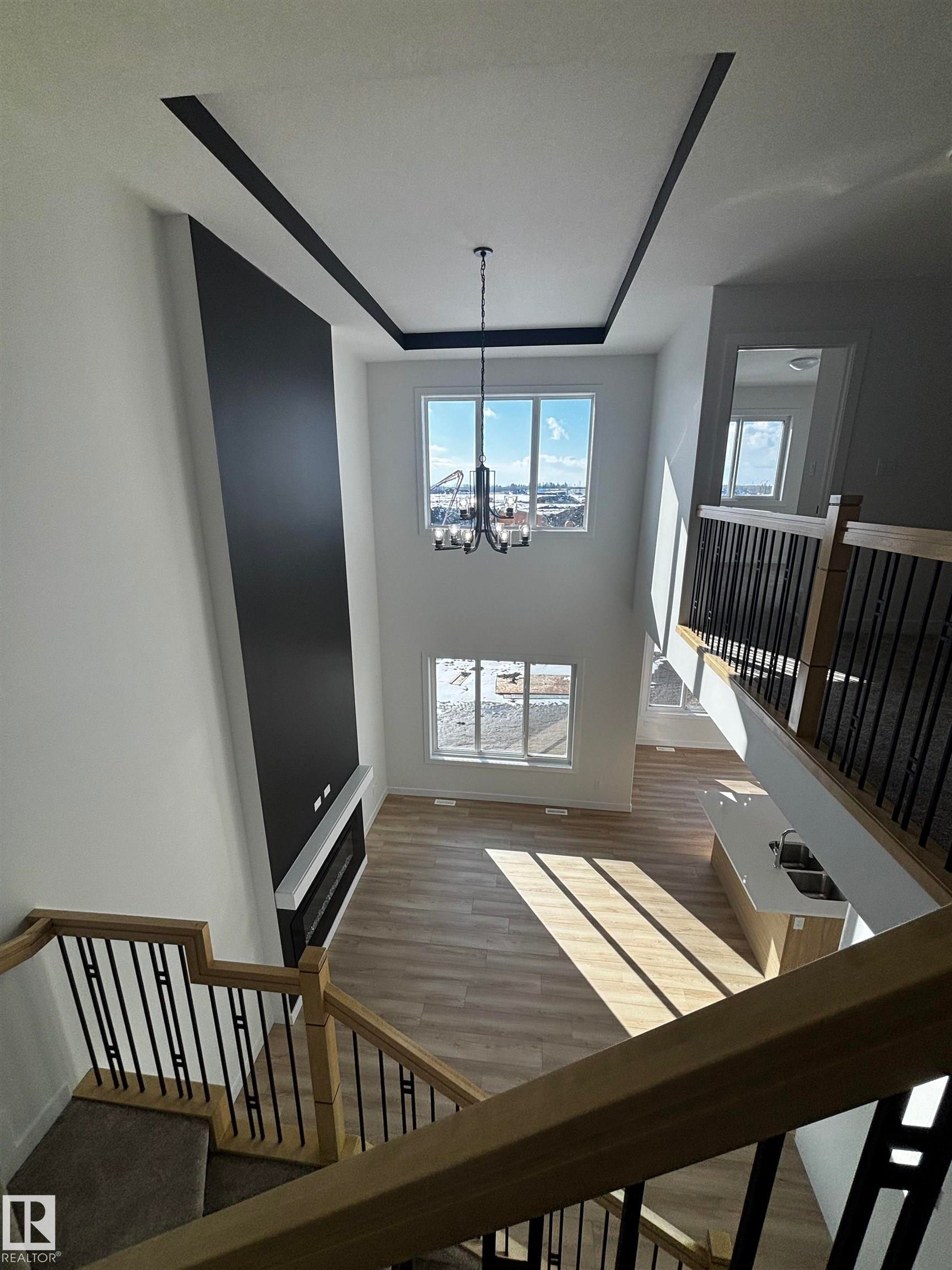 The main living area boasts high ceilings with decorative trim, large windows providing expansive views, and light-toned flooring - 2012 210 St, Edmonton, AB - Indoor Photo Showing Other Room
