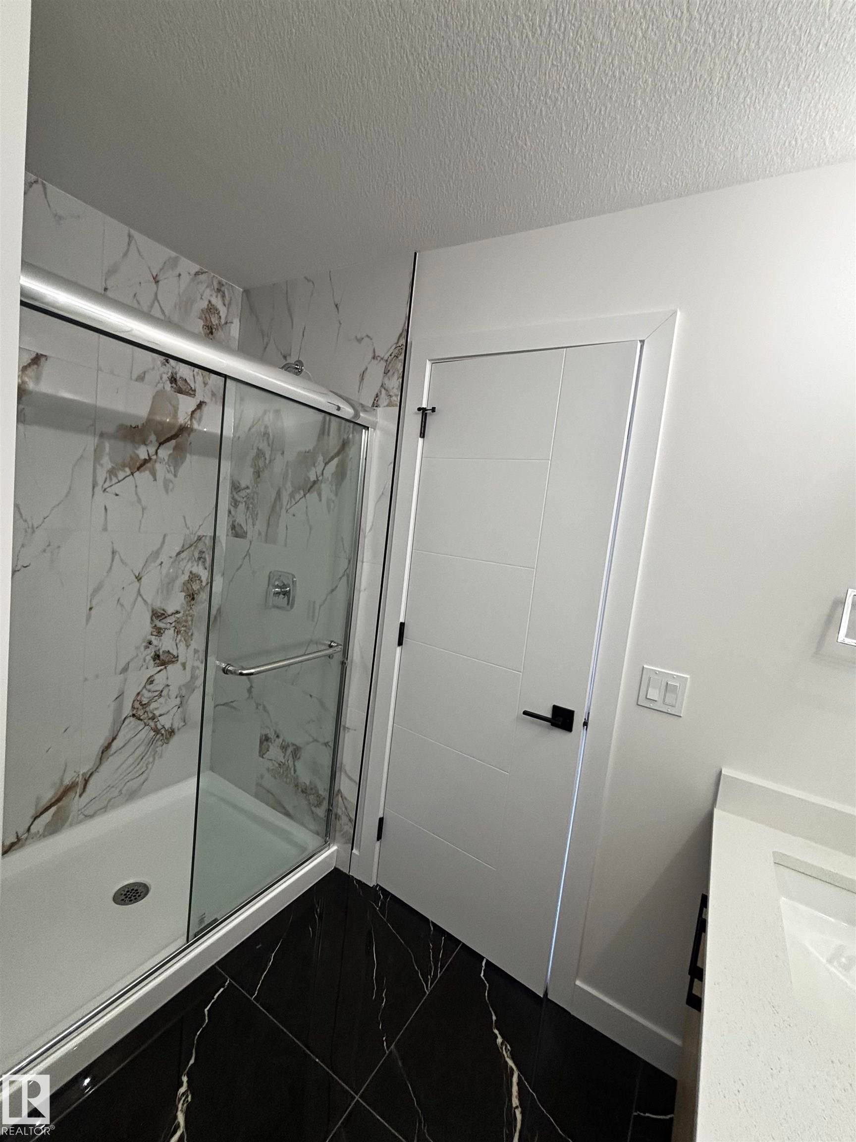 This bathroom features a contemporary shower with a glass enclosure and marble-look wall tiling - 2012 210 St, Edmonton, AB - Indoor
