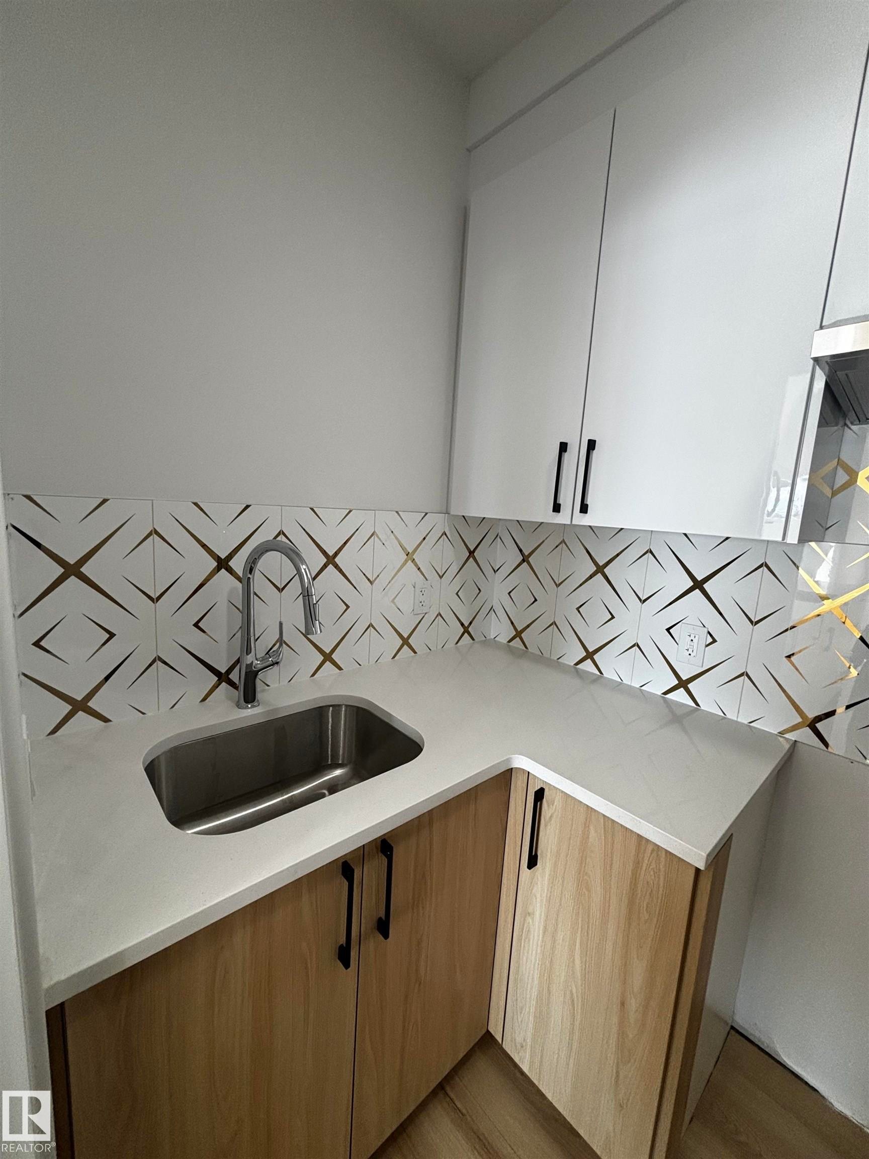 Utility area featuring a stainless steel sink, light-colored countertops, and patterned backsplash - 2012 210 St, Edmonton, AB - Indoor Photo Showing Kitchen With Double Sink