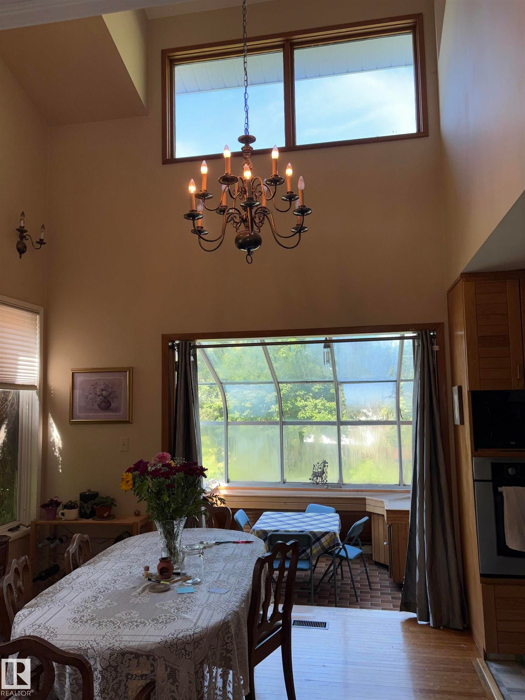 Two-story interior space featuring a wrought iron chandelier and coordinating wall sconces - 8812 146 Street, Edmonton, AB