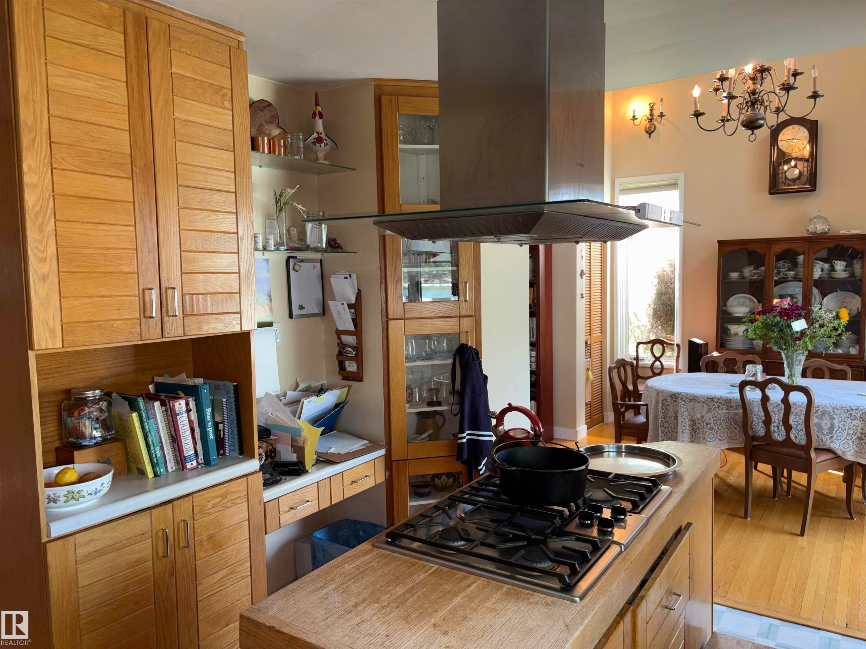 Kitchen featuring a built-in cooktop with an overhead stainless steel range hood, natural wood cabinetry, and a light-toned countertop - 8812 146 Street, Edmonton, AB
