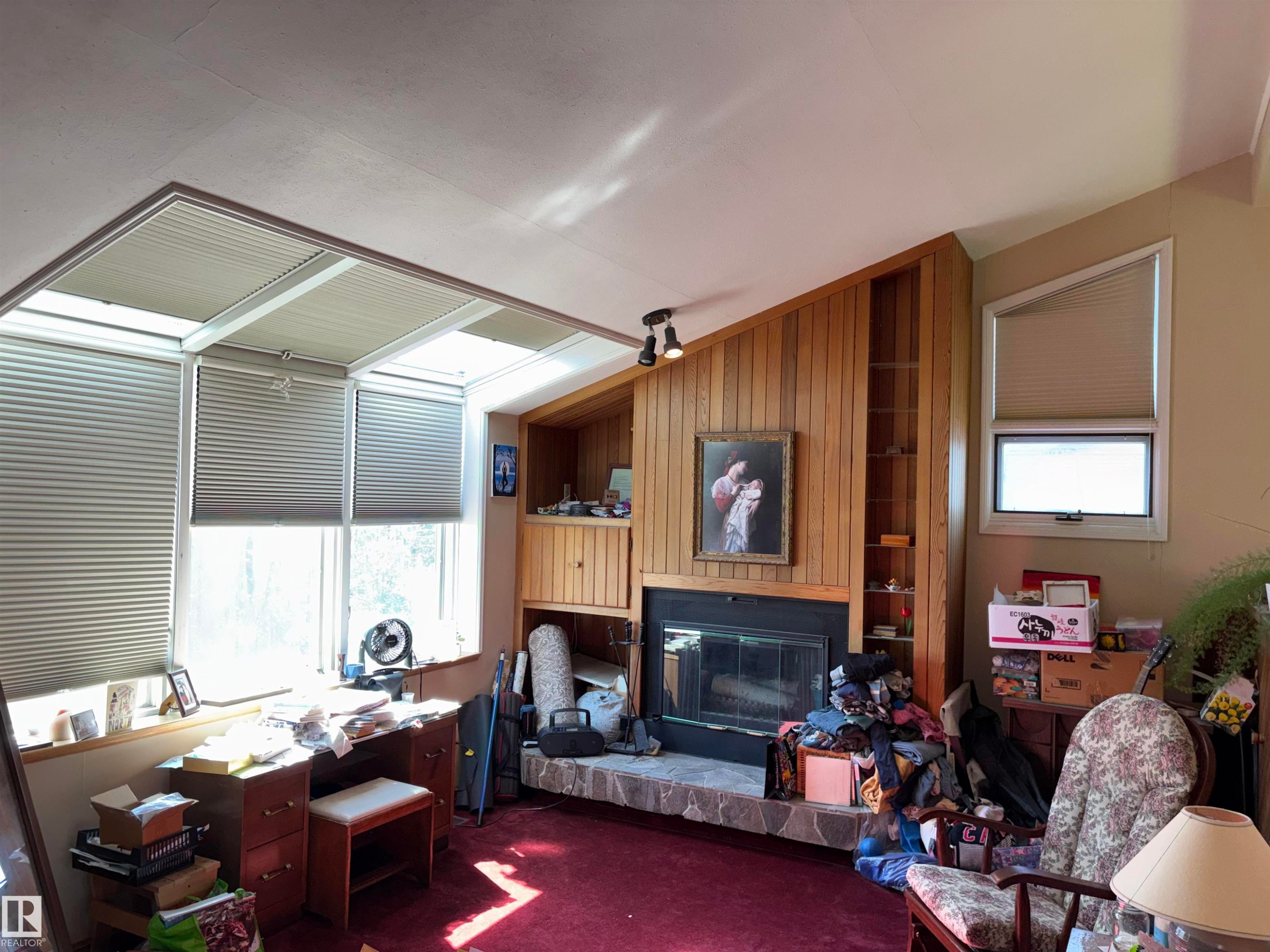 Stone-surround fireplace with a black insert, flanked by wood paneling and built-in shelving - 8812 146 Street, Edmonton, AB