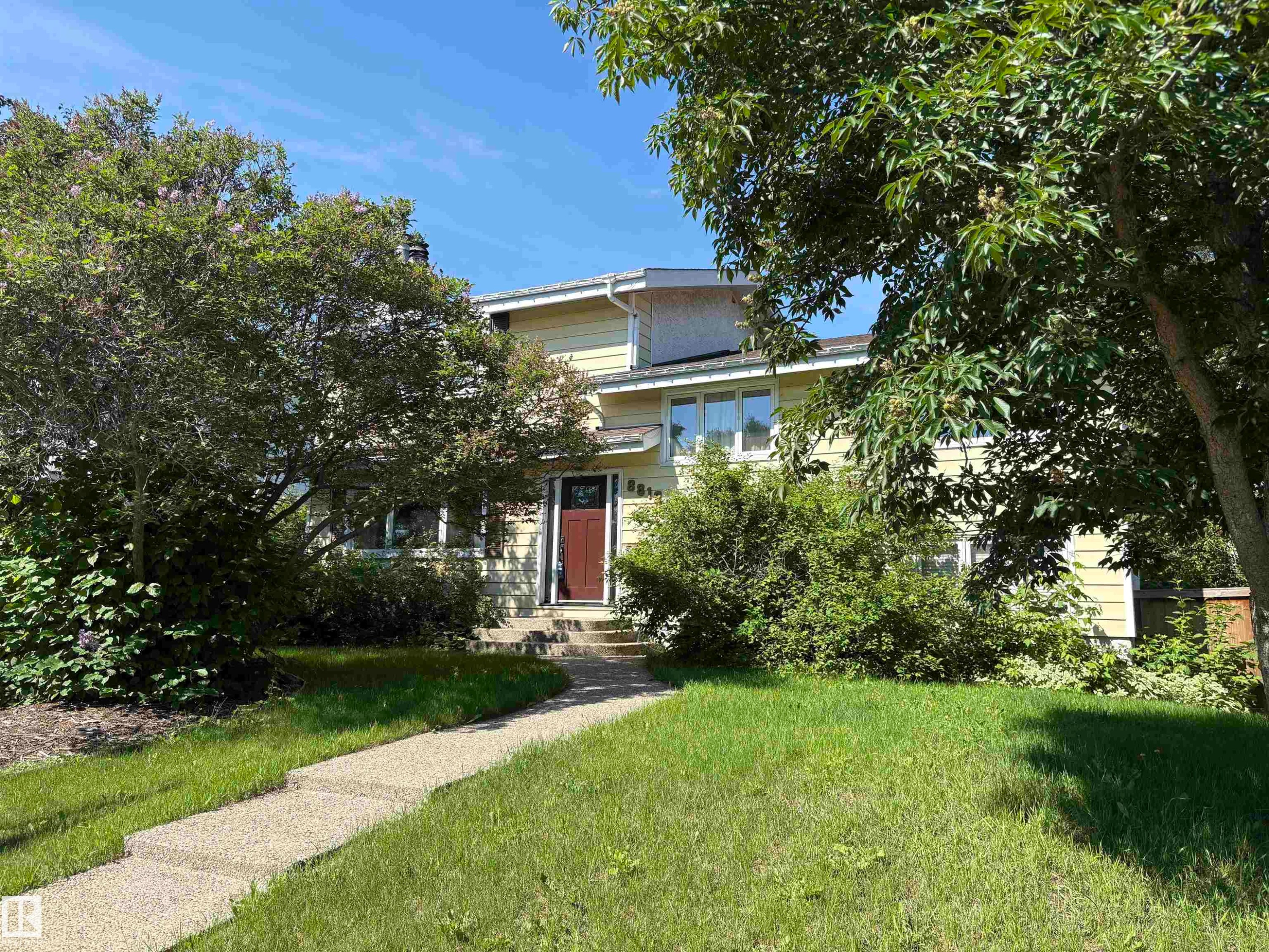 Two-story residence featuring light yellow siding and a prominent dark red entry door - 8812 146 Street, Edmonton, AB